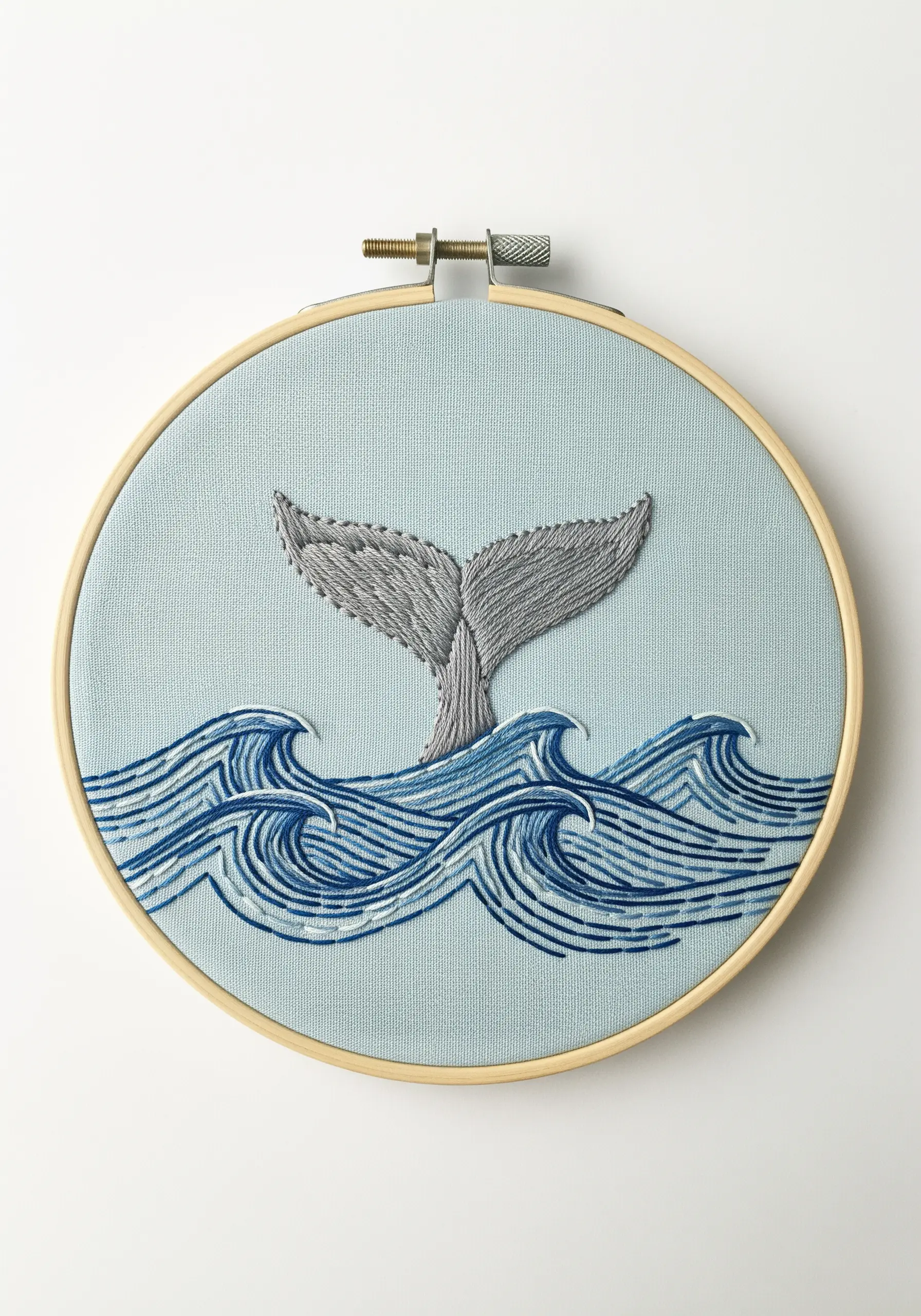 A whale tail diving into stylized embroidered waves made of layered blue lines.