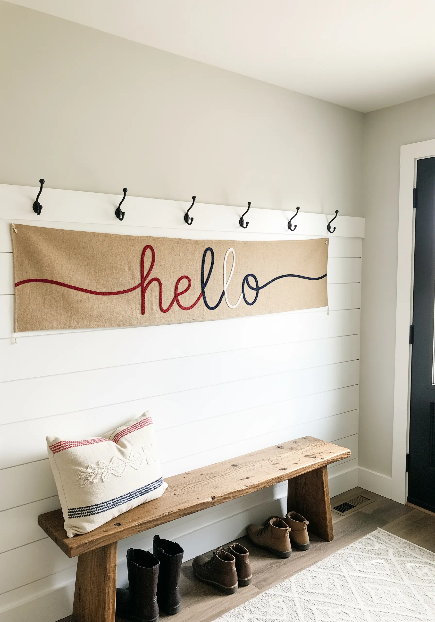 A burlap banner with the word 'hello' embroidered in thick, tri-colored yarn.