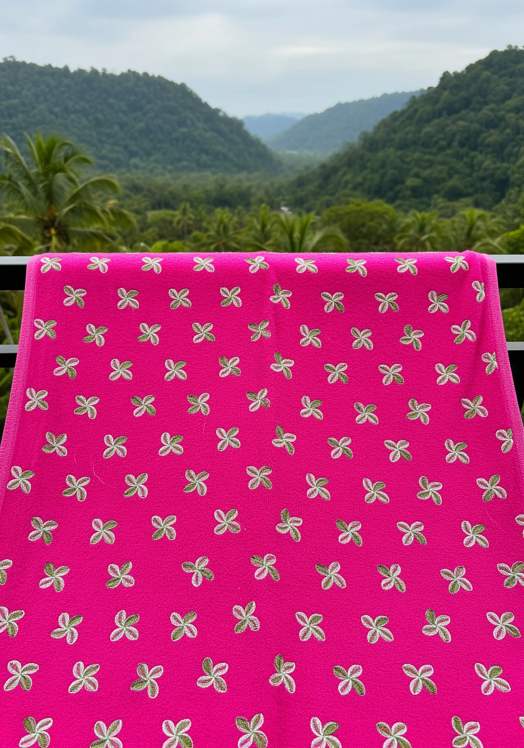 A repeating pattern of small, four-leaf clovers in variegated thread on a bright pink towel.