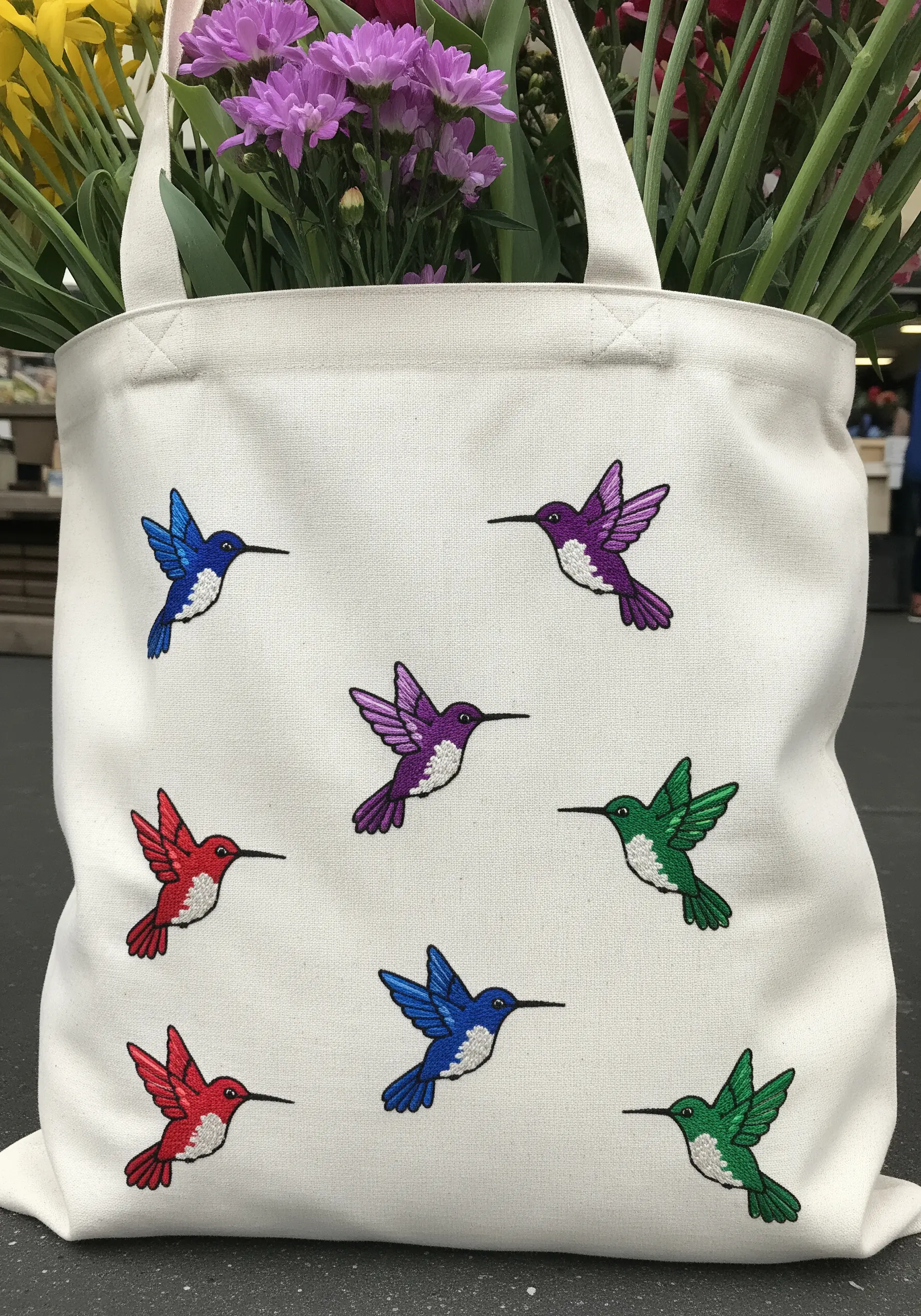 A scattered pattern of small embroidered hummingbirds in red, blue, purple, and green.