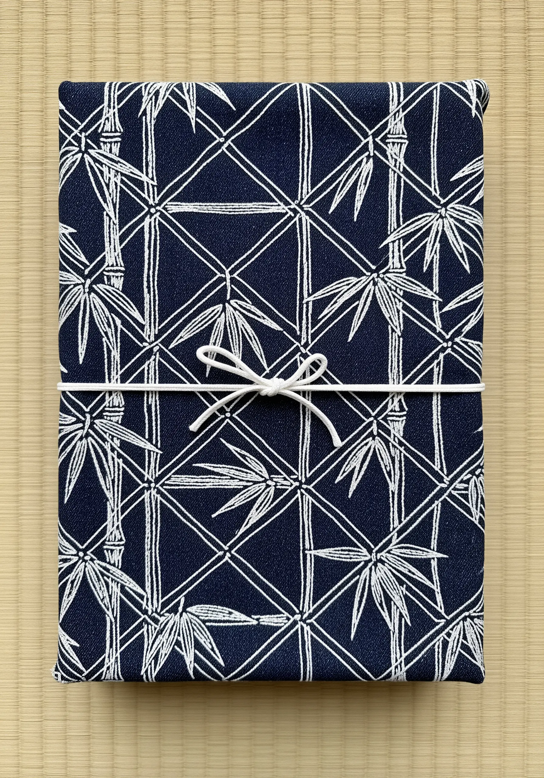 A geometric pattern of white bamboo stalks and leaves on a dark navy fabric.