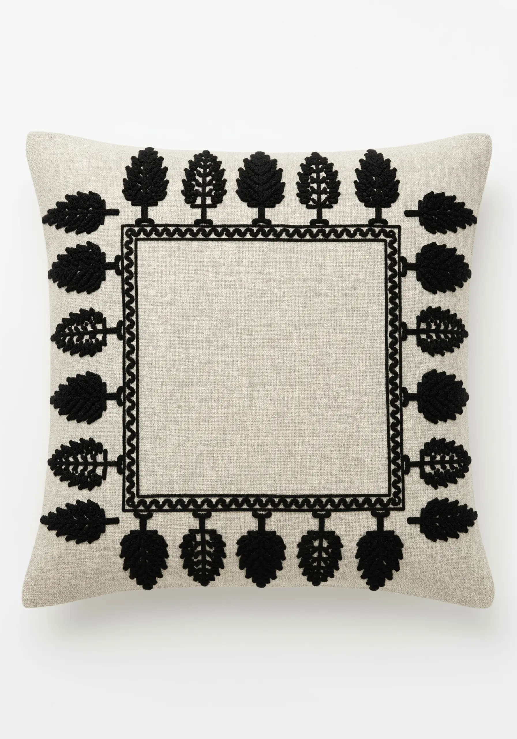 A graphic border of black embroidered trees and leaves on a neutral cushion