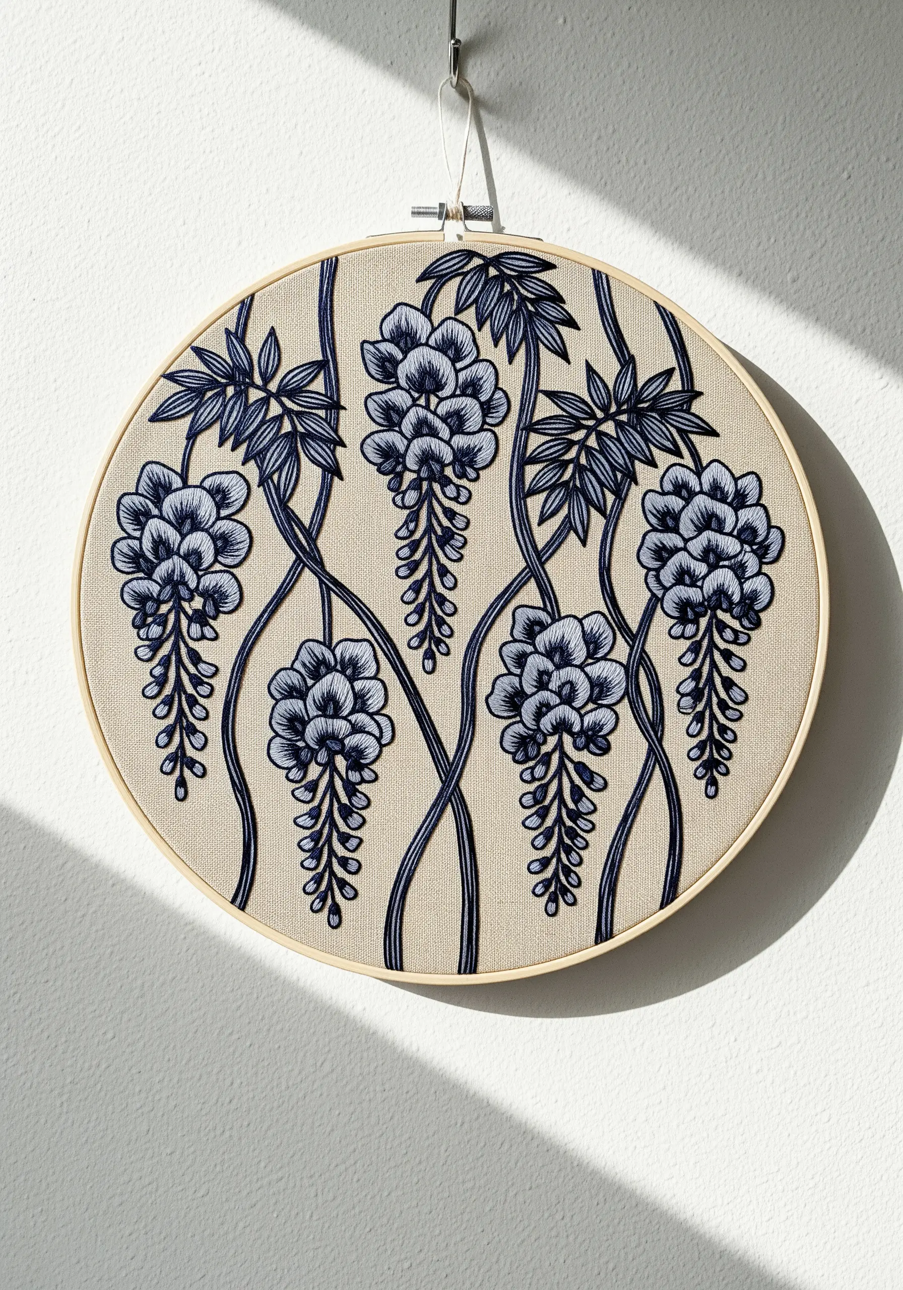 Blue and black wisteria embroidery with intertwining vines on beige fabric.