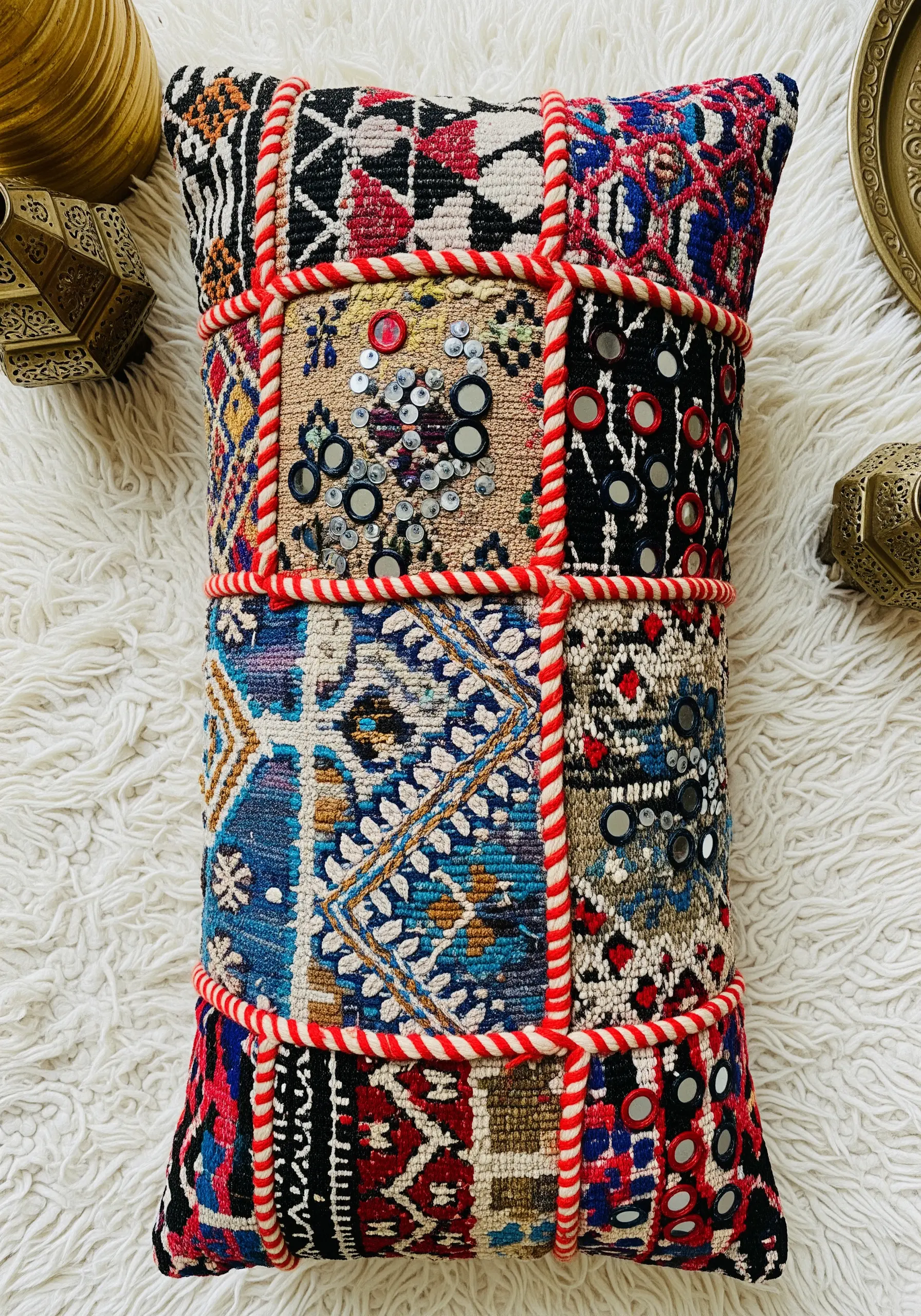 A vibrant patchwork cushion combining appliqué, mirror work, and couched cord