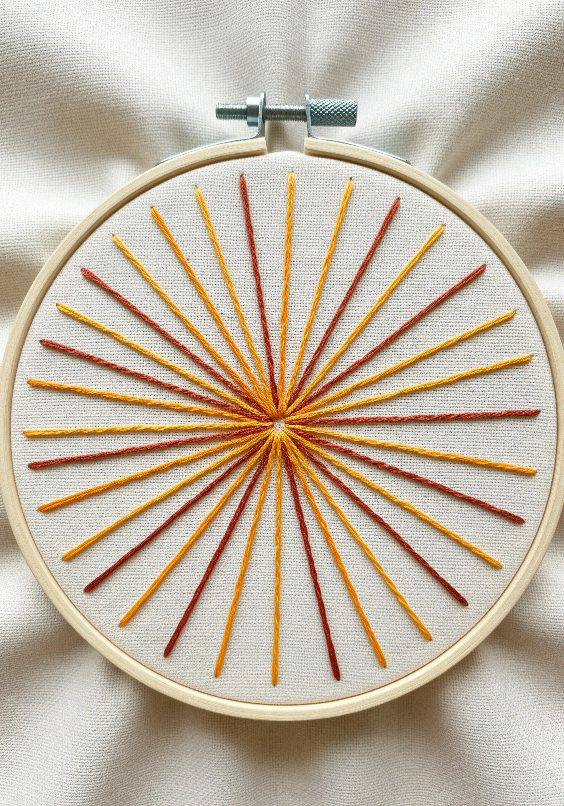 A geometric sunburst embroidered with radiating straight stitches in yellow, orange, and red.