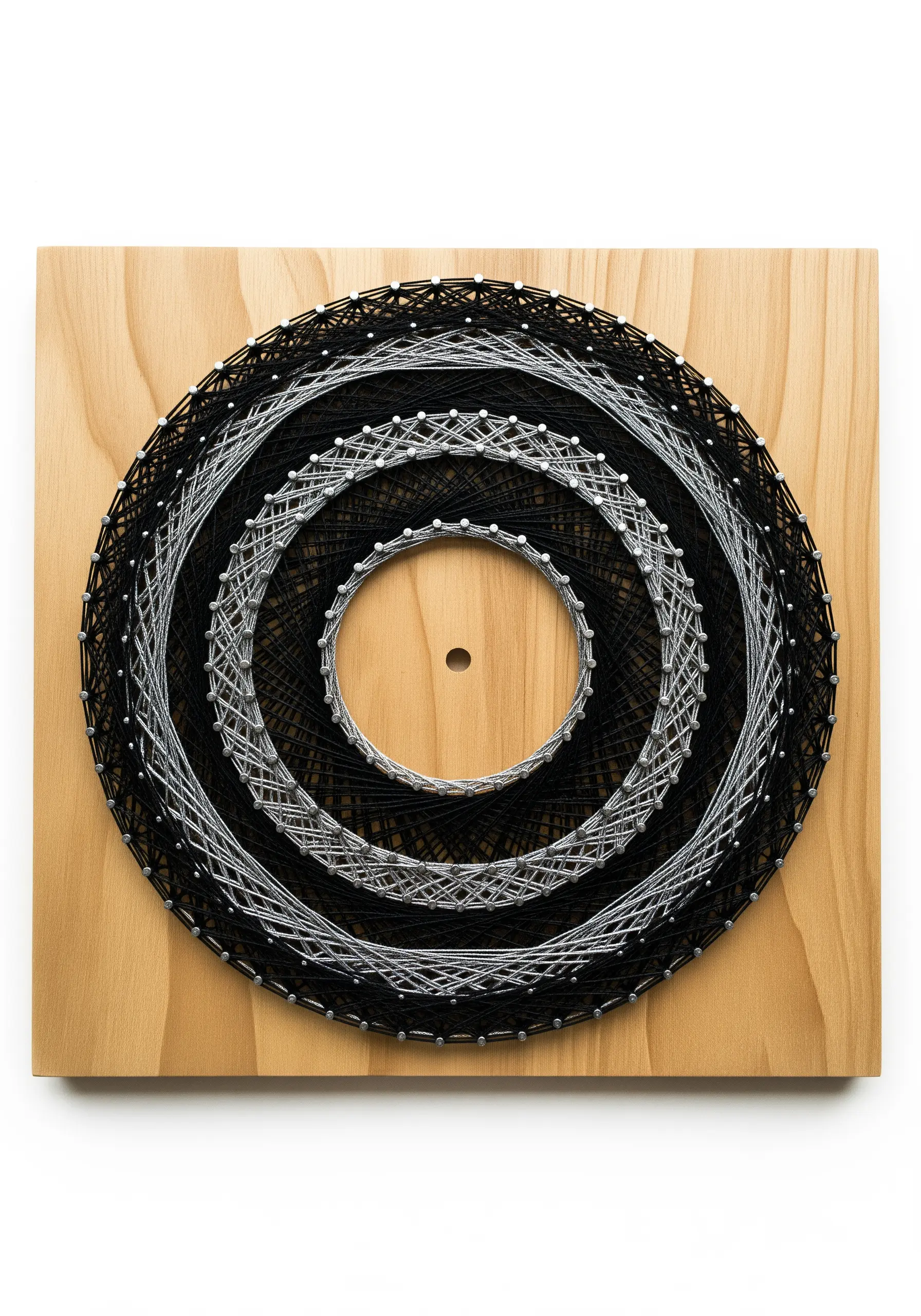Monochrome string art of concentric circles in black and white on a light wood board