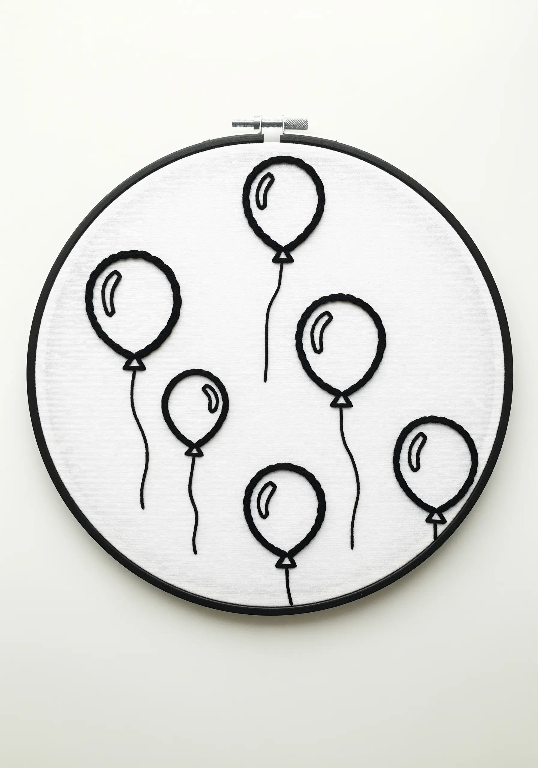 Minimalist black outlines of floating balloons on white fabric in a black hoop.