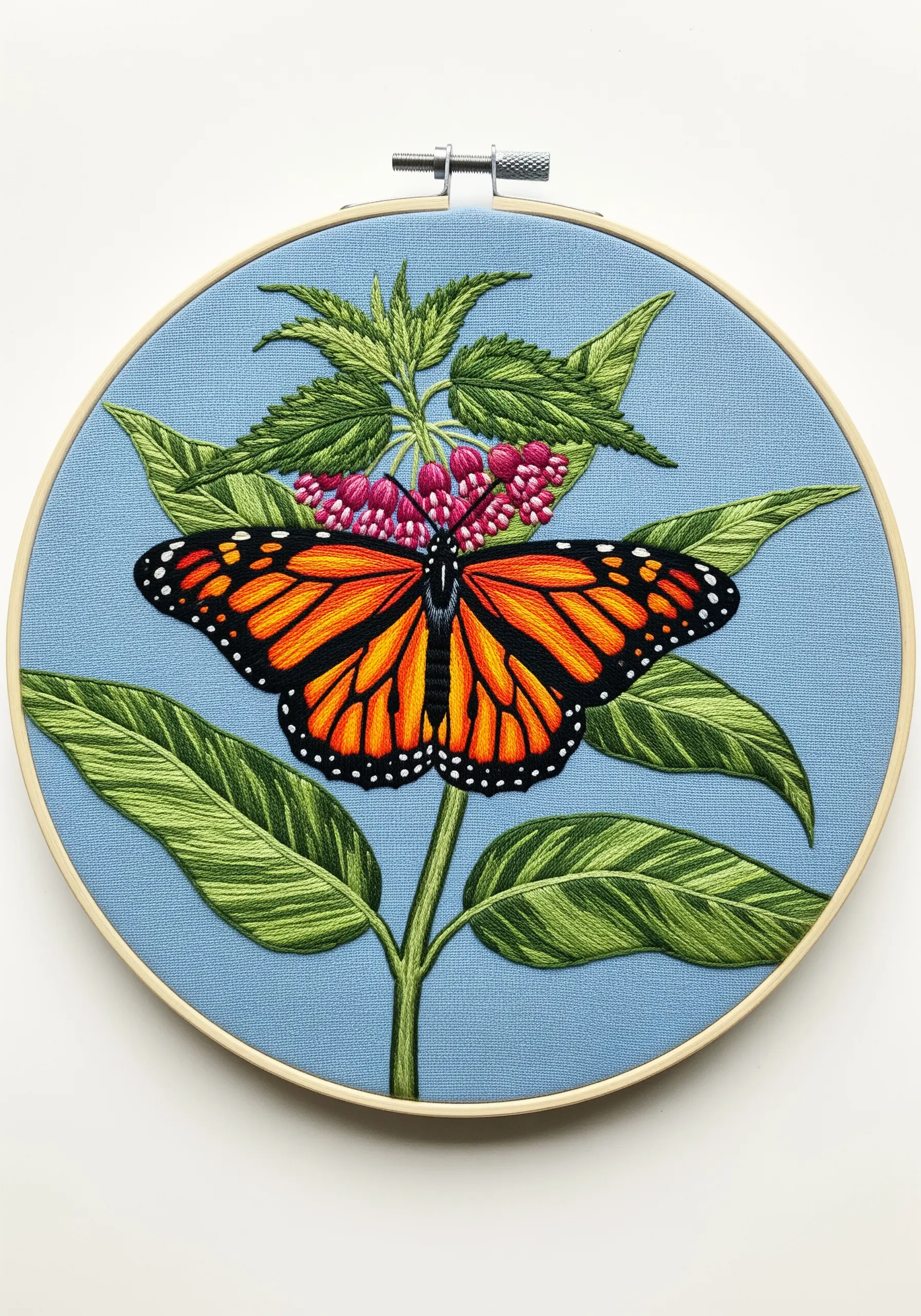 A vibrant monarch butterfly embroidered on milkweed, using bold, naturally dyed threads.