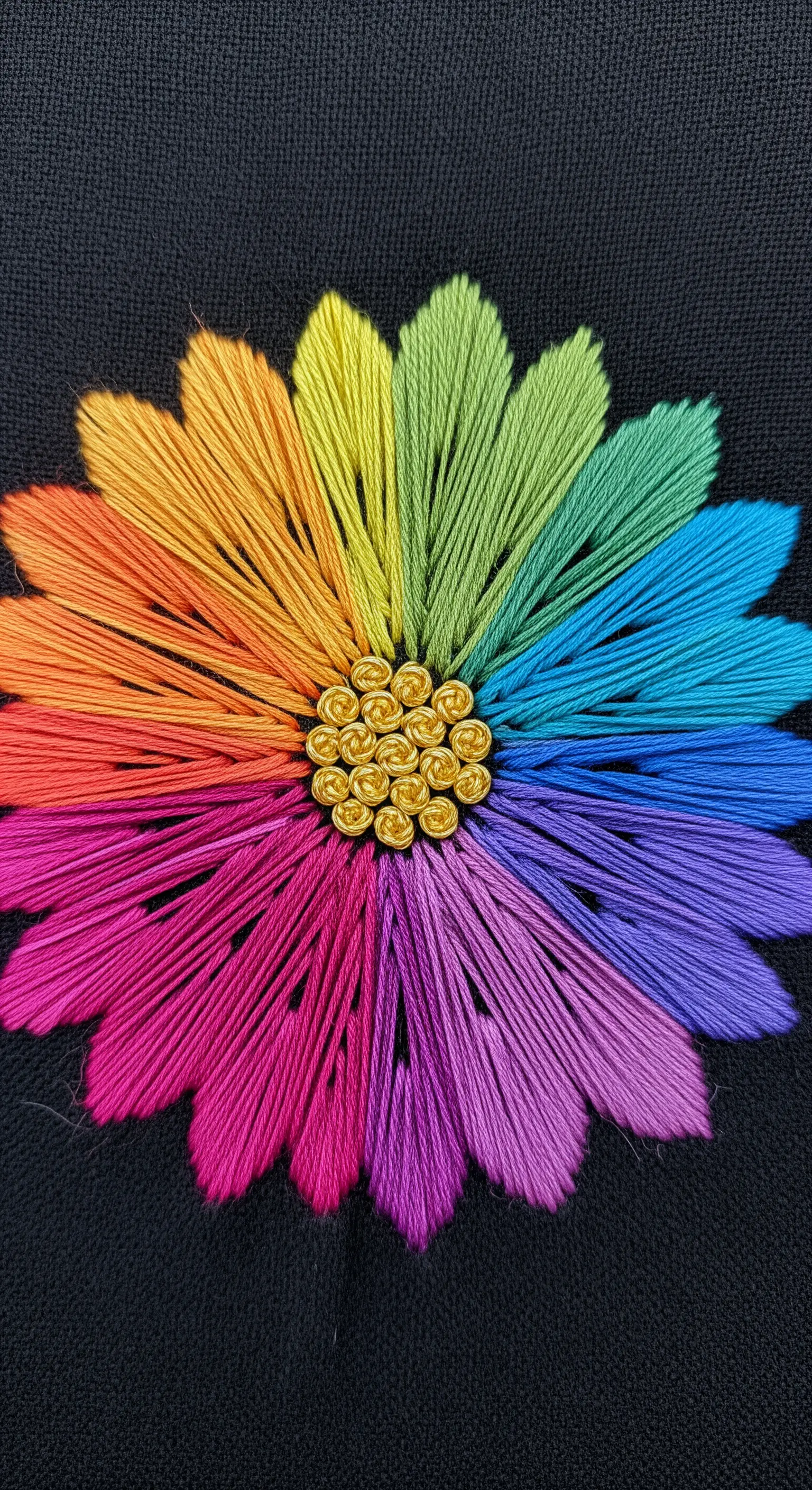A vibrant rainbow flower made with straight stitch petals on black fabric.