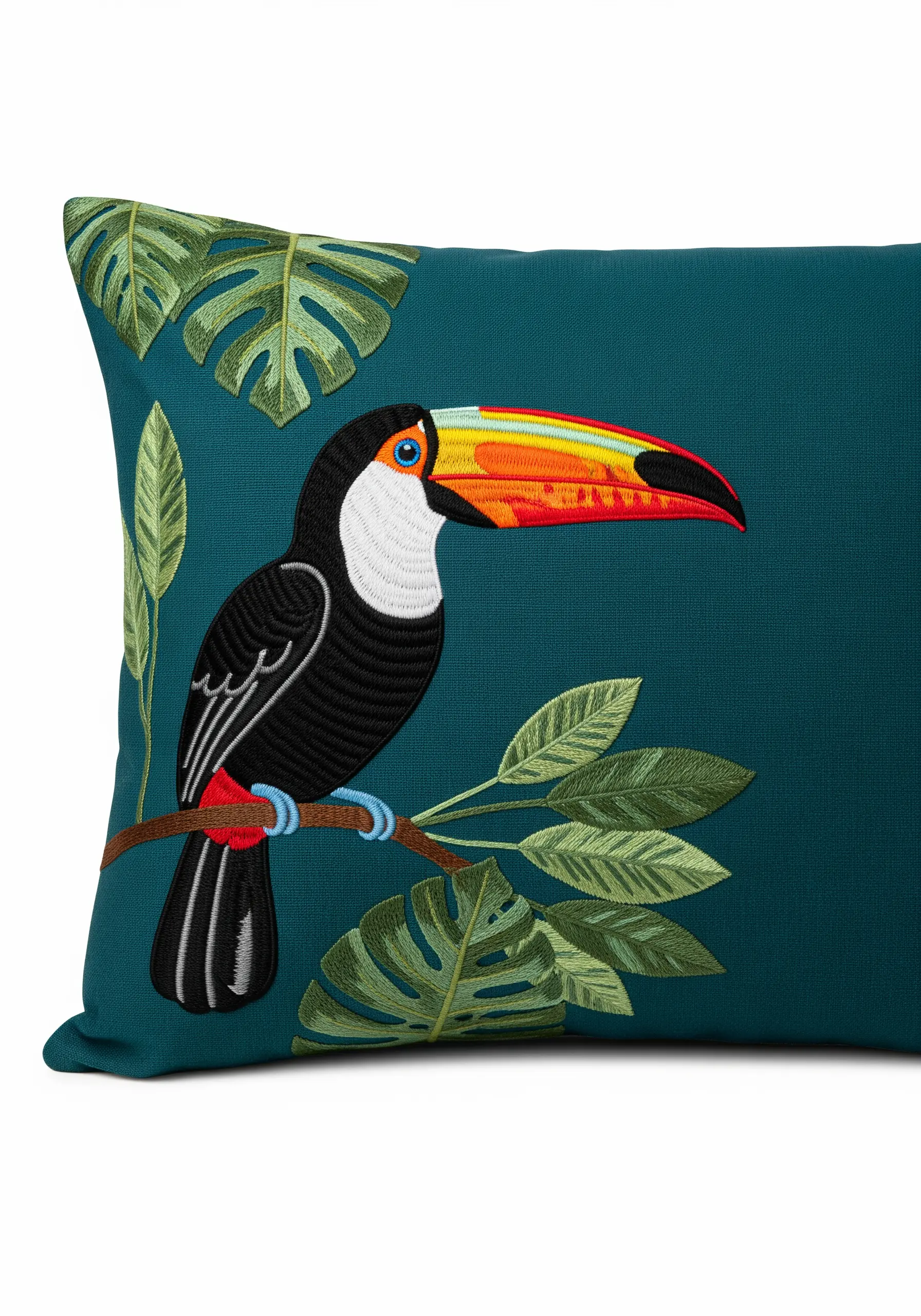 Embroidered toucan with a brightly colored, satin-stitched beak on a teal pillow.