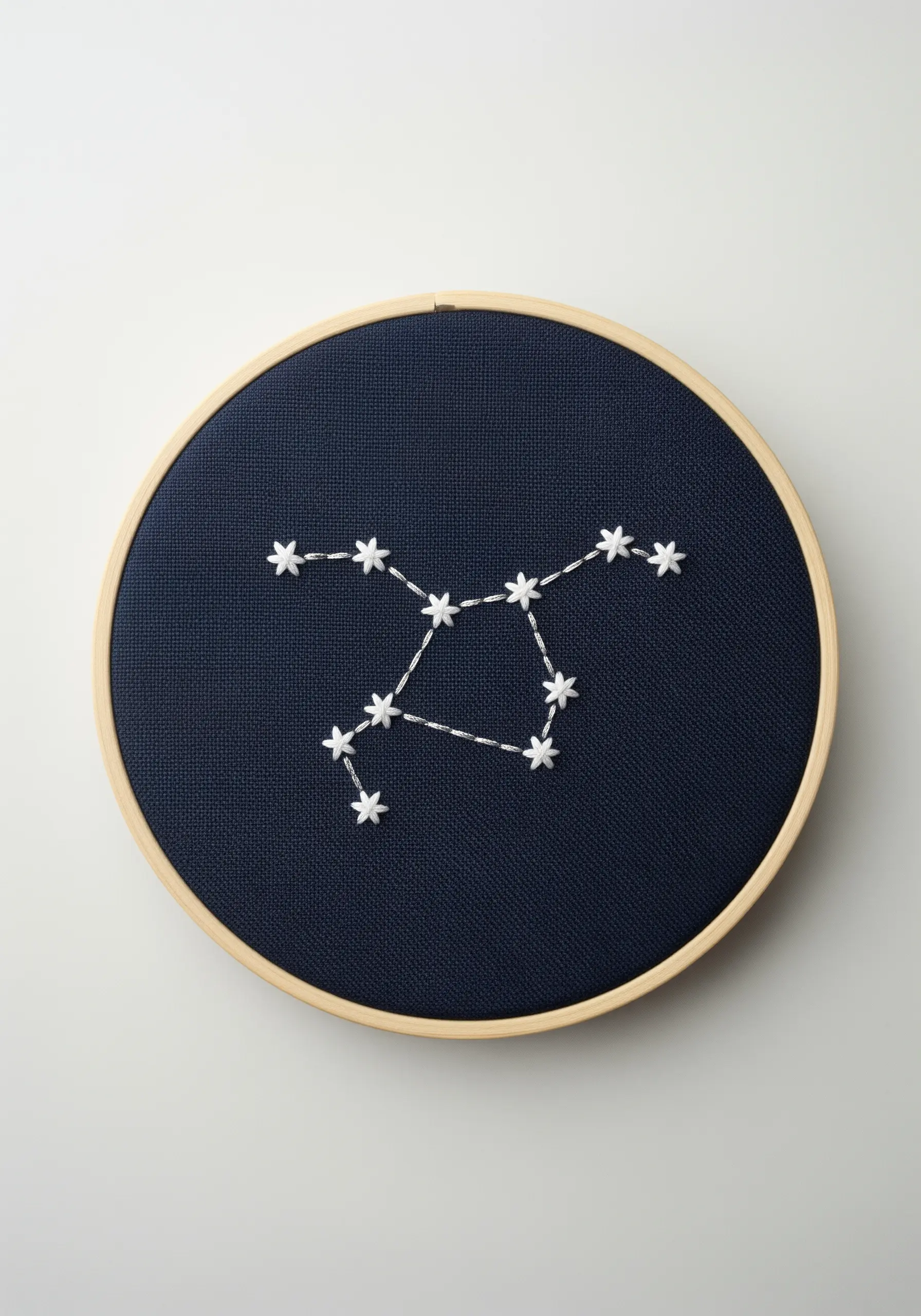 A constellation stitched in white on navy fabric, with stars made of lazy daisy stitches.