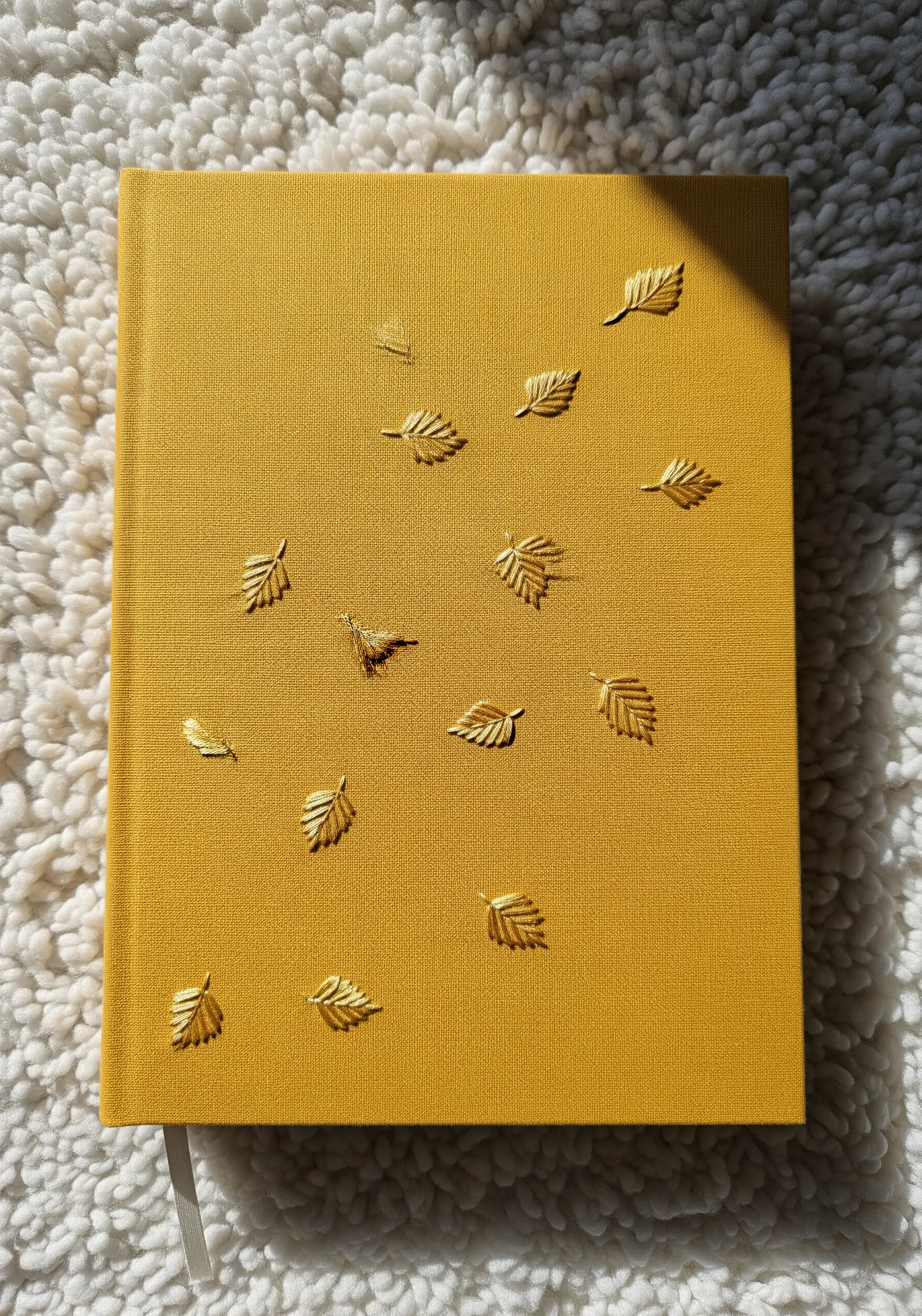 Small, scattered golden leaves with a raised 3D effect on a mustard-yellow journal.