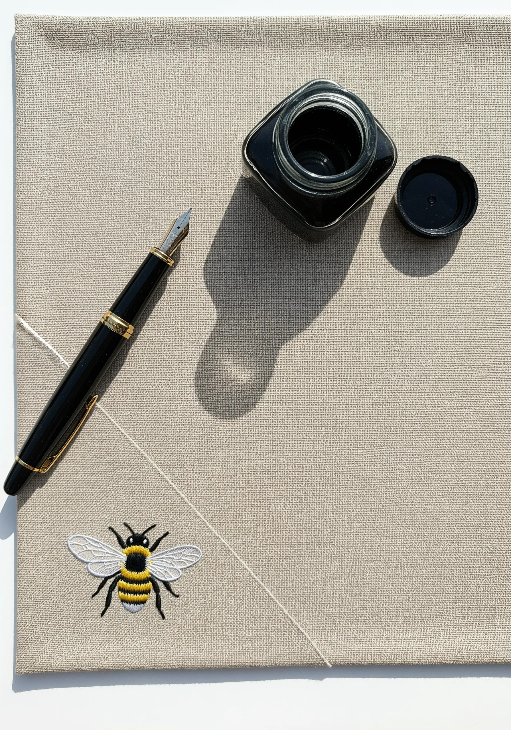 A realistic embroidered bee with translucent organza appliqué wings on a desk blotter