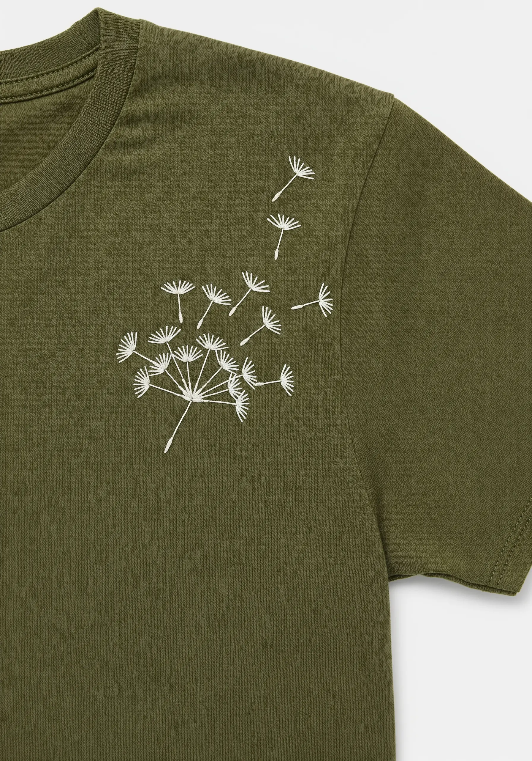An embroidered dandelion with seeds blowing across an olive green t-shirt.