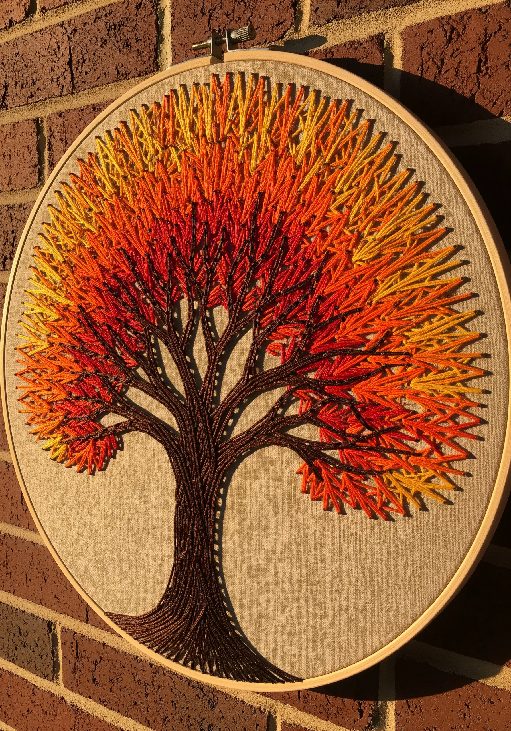 String art autumn tree with a yellow, orange, and red ombré effect on its leaves.