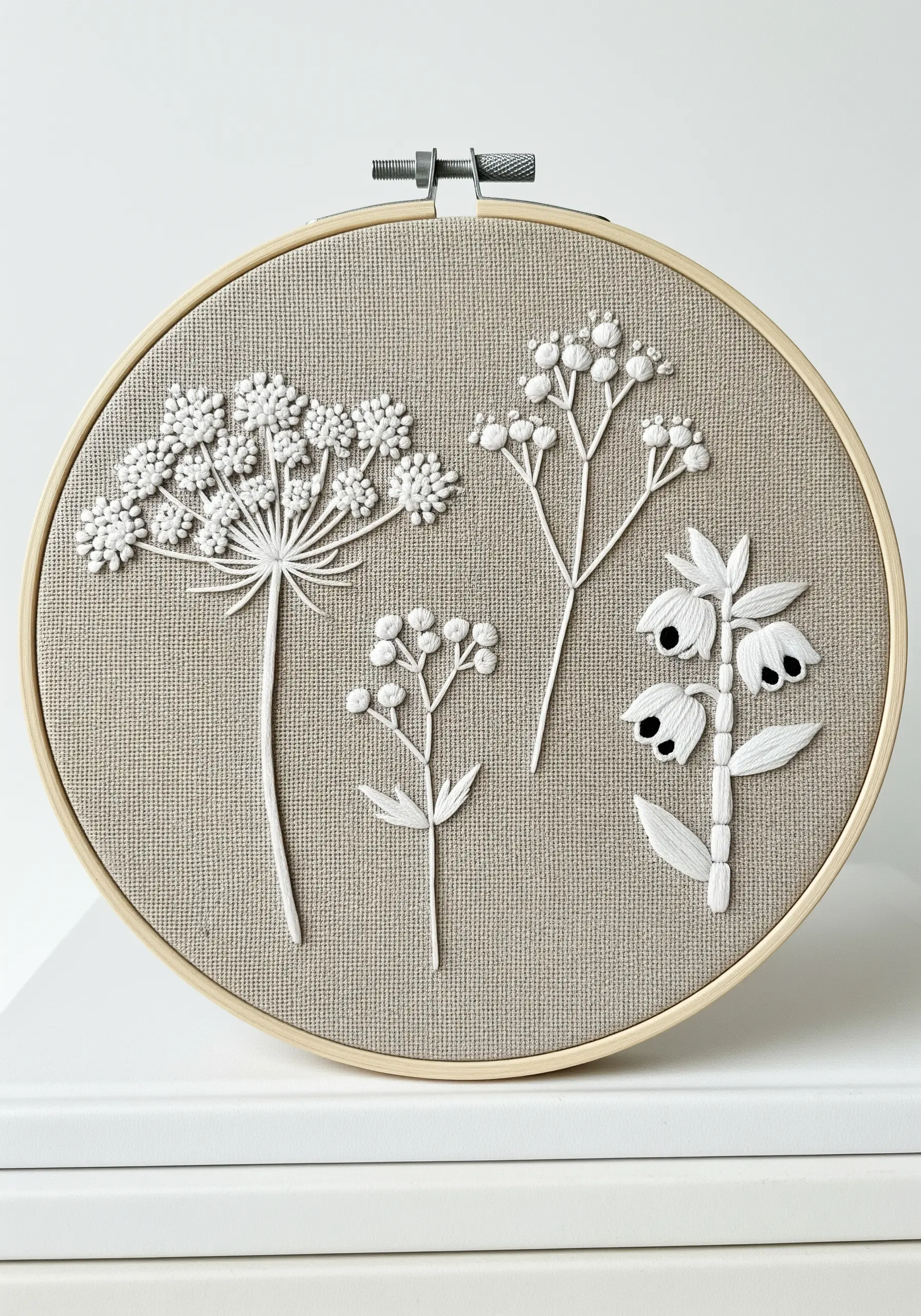 White-on-beige embroidery of floral silhouettes using French knots and padded satin stitch.