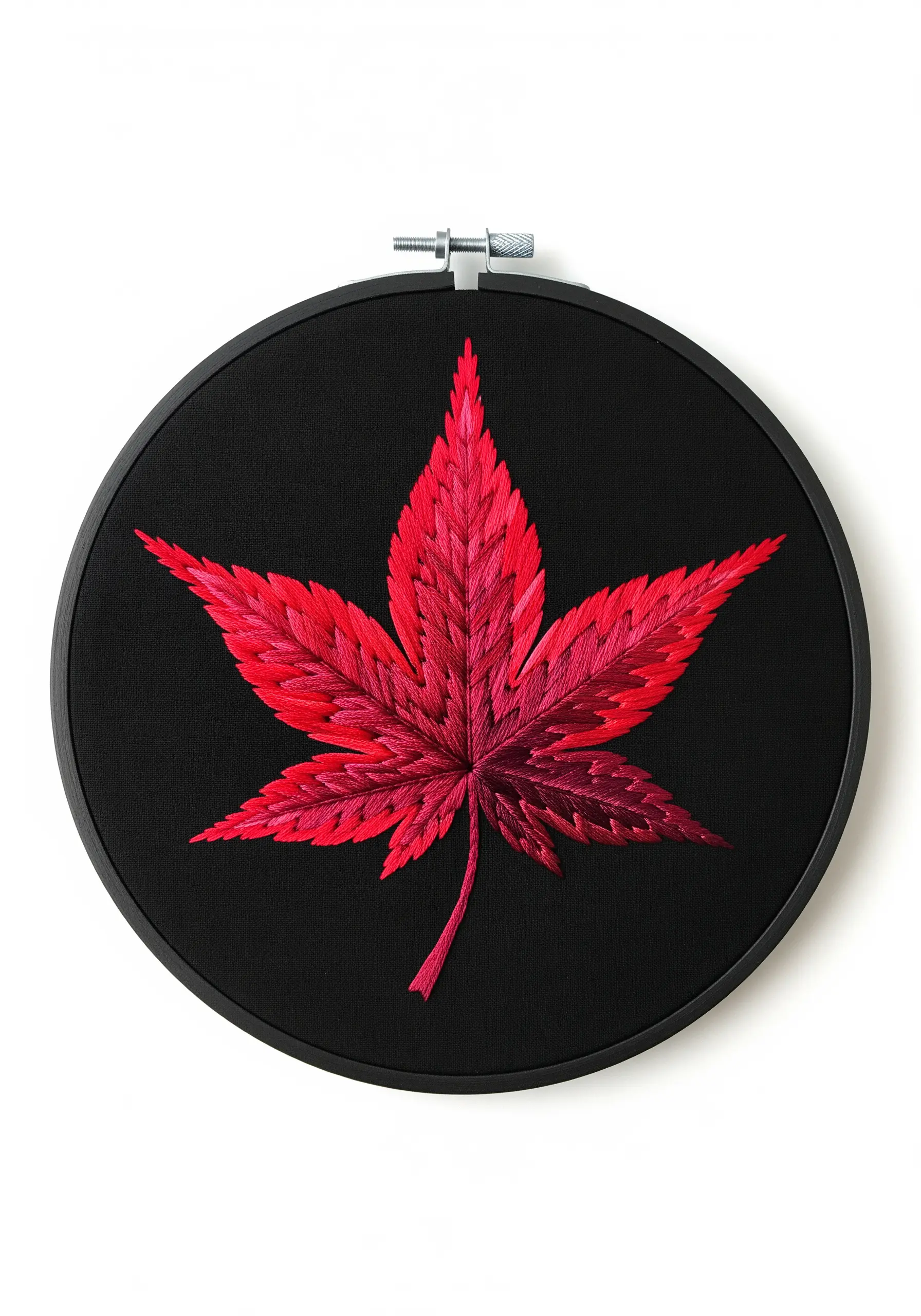 A vibrant red Japanese maple leaf created with thread painting on a solid black fabric background.
