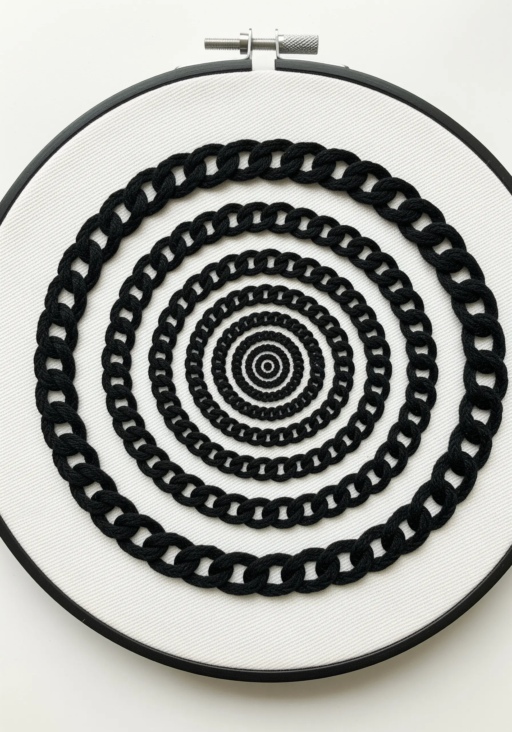 Concentric circles of black chain stitch on white fabric creating an optical illusion.