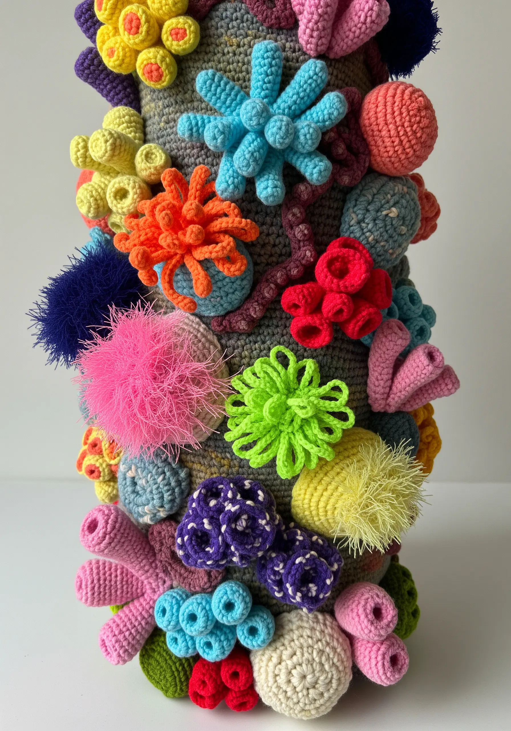 A vibrant, 3D crocheted sculpture of a coral reef with various textures and colors.