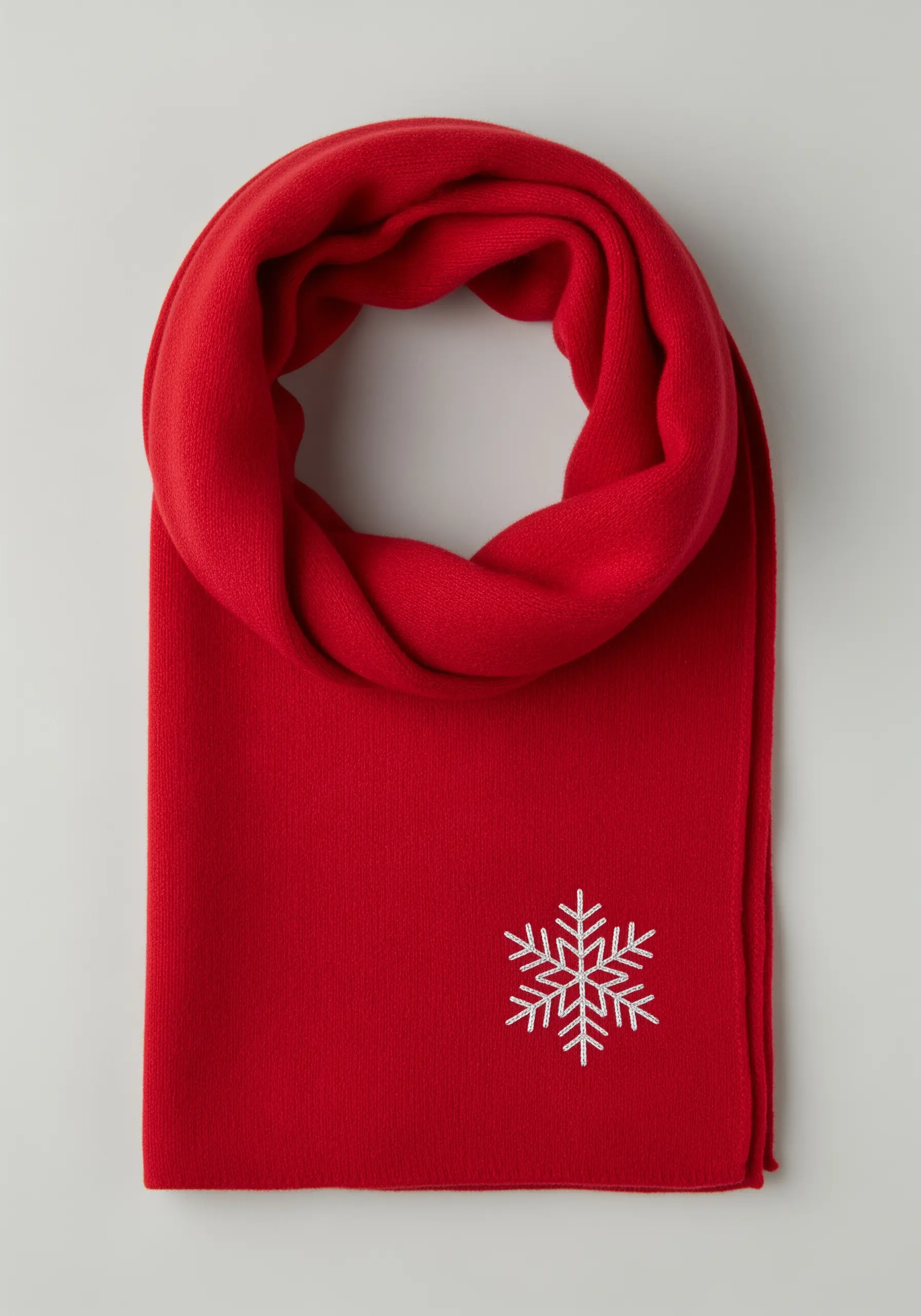 A white embroidered snowflake with geometric, crystalline arms on a bright red scarf.