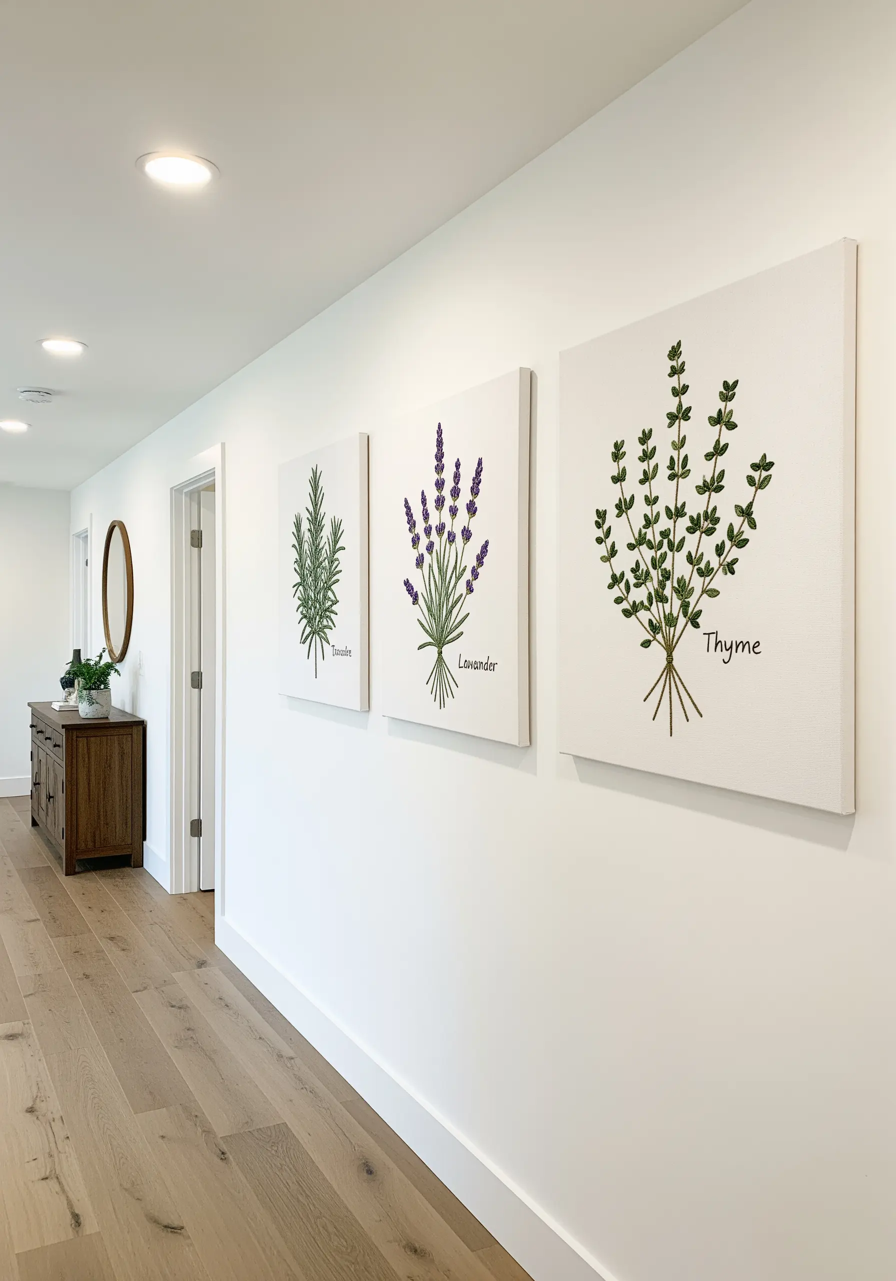 A trio of white canvases, each featuring a different embroidered herb: rosemary, lavender, and thyme.
