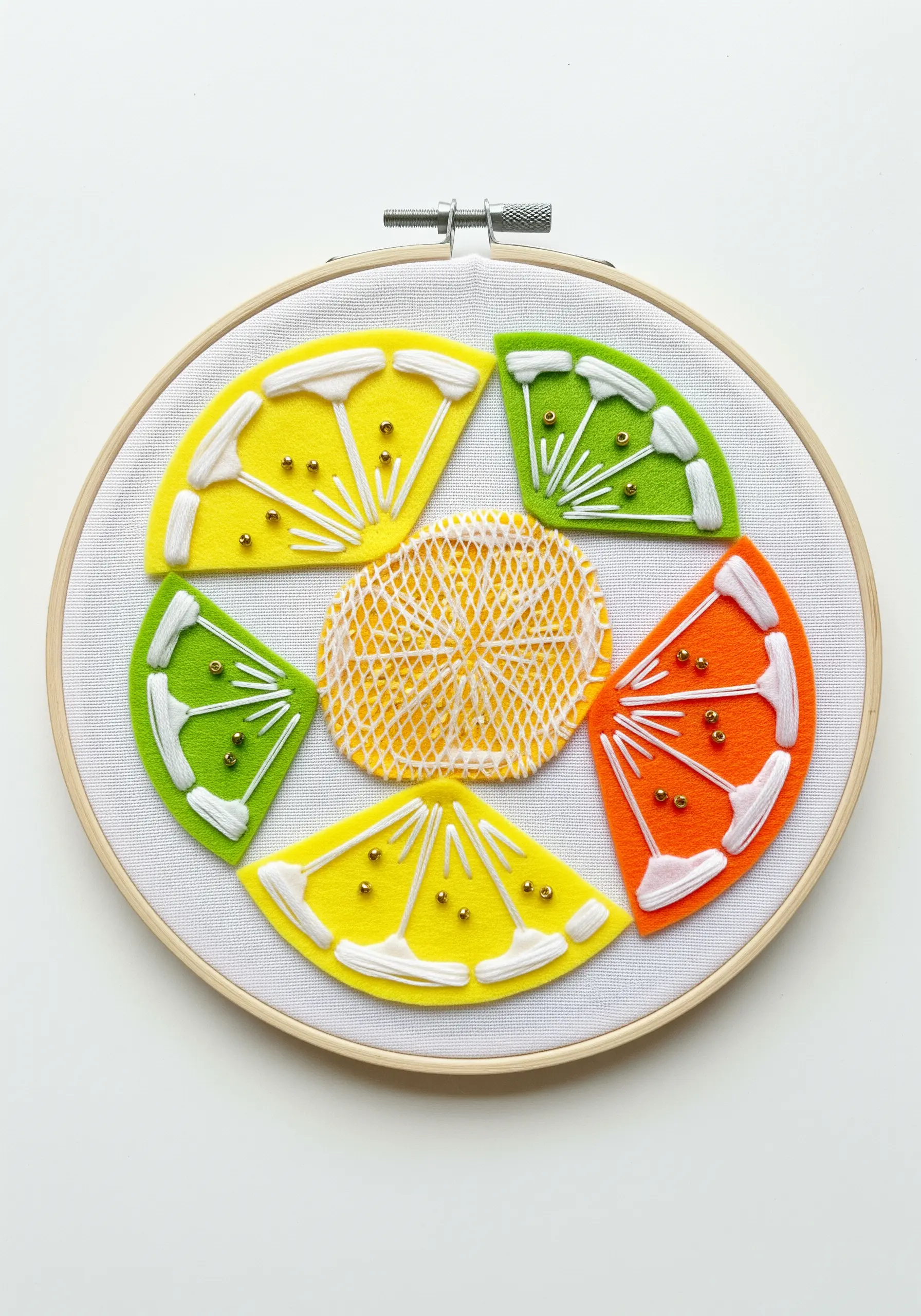 Citrus slice design using felt appliqué with radiating white stitches and gold seed beads.
