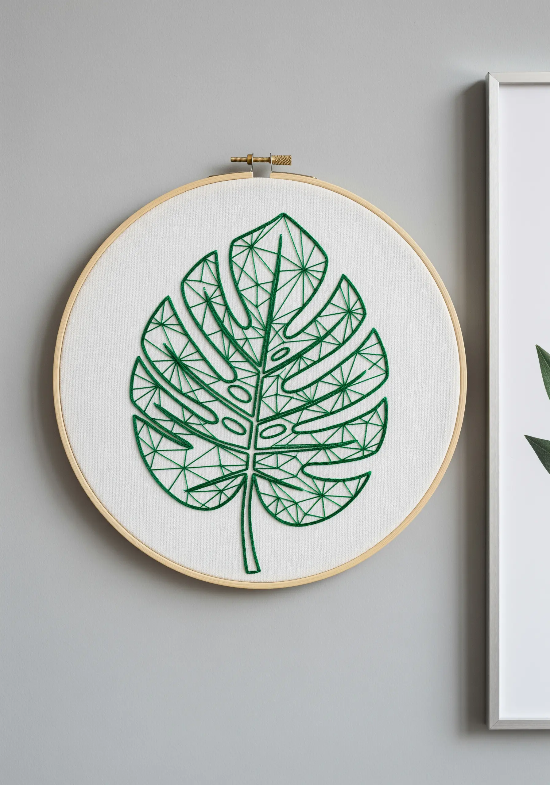 A geometric line art embroidery of a monstera leaf in bright green thread.