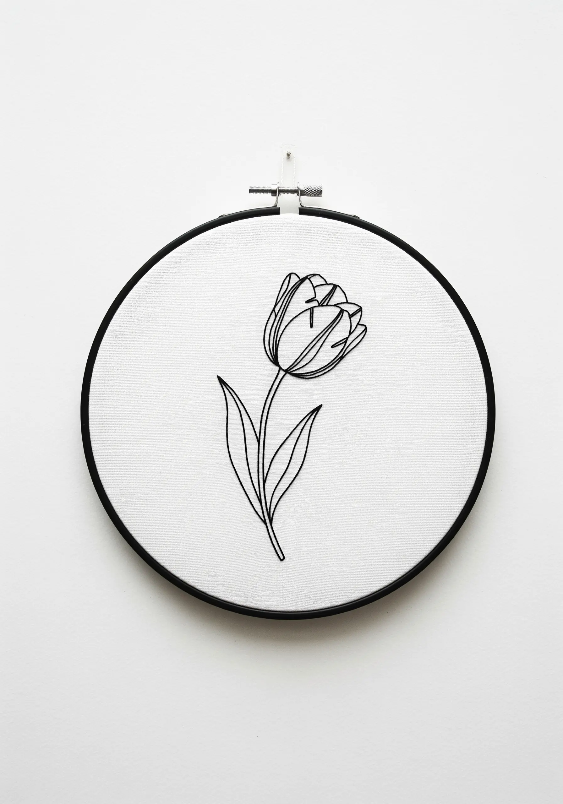 Minimalist black line art embroidery of a single tulip in a modern black hoop.