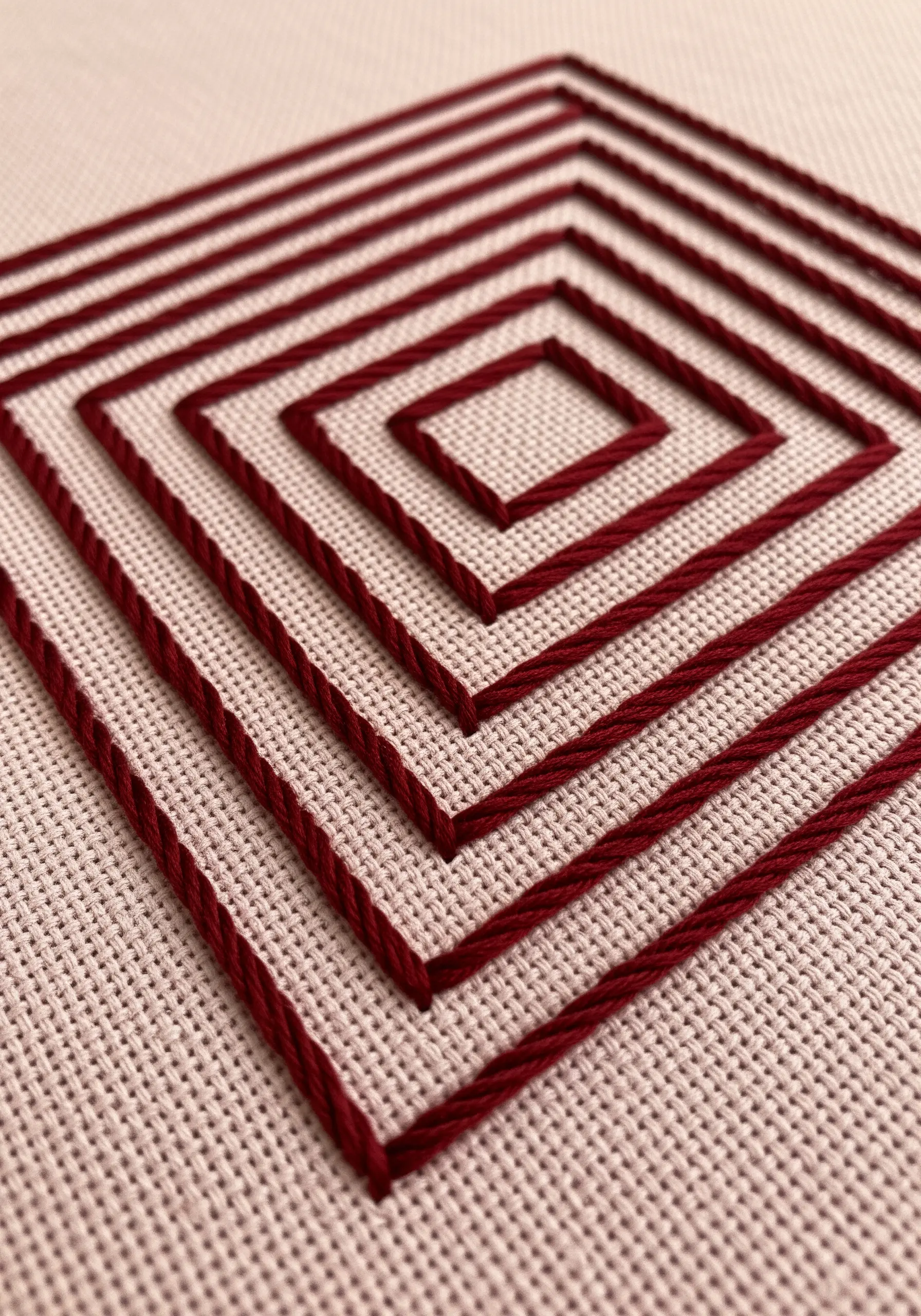 Concentric squares embroidered in burgundy thread using a whipped backstitch for clean lines.