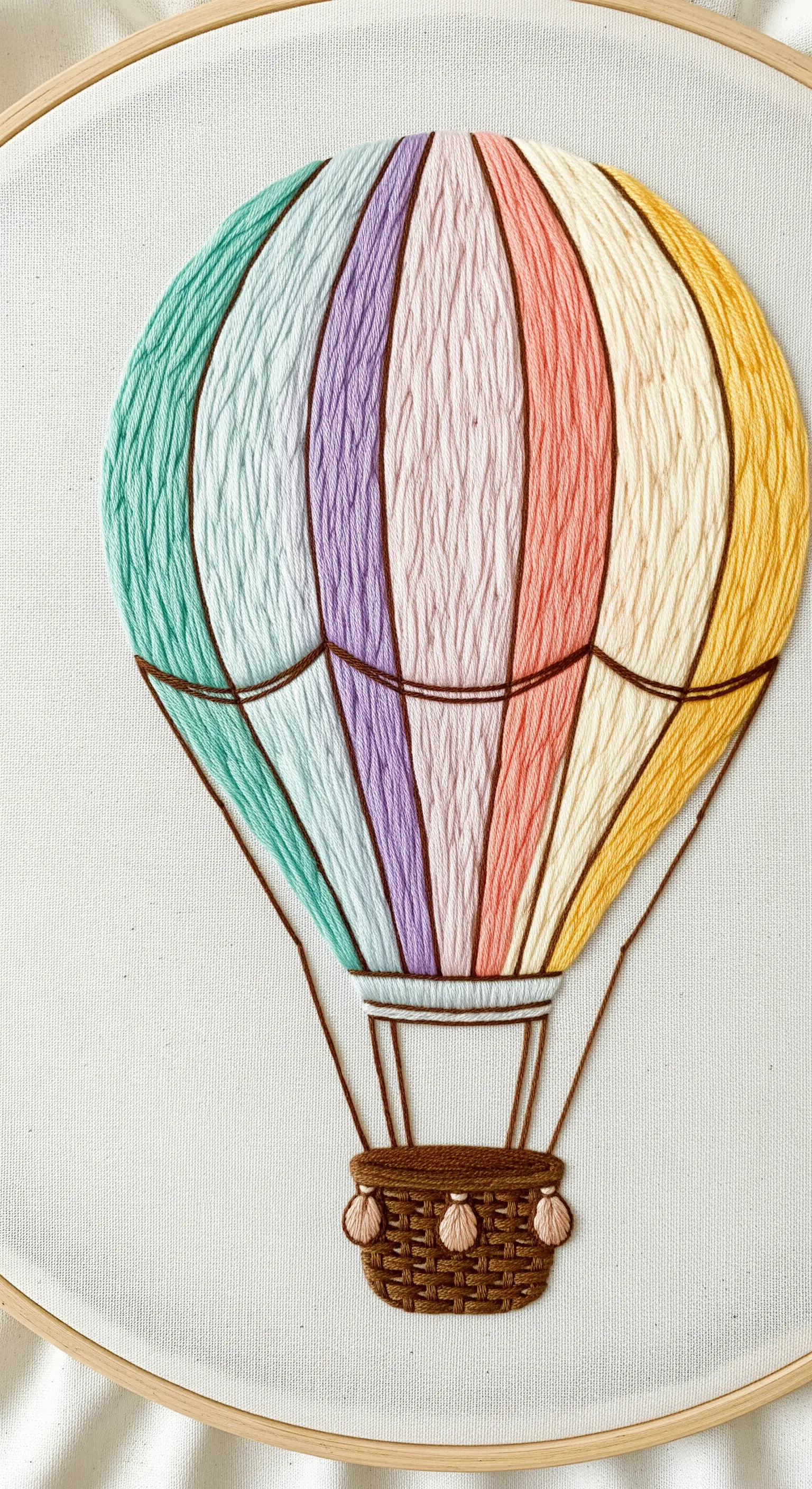 A hot air balloon with vertical panels of pastel rainbow satin stitch and dark outlines.