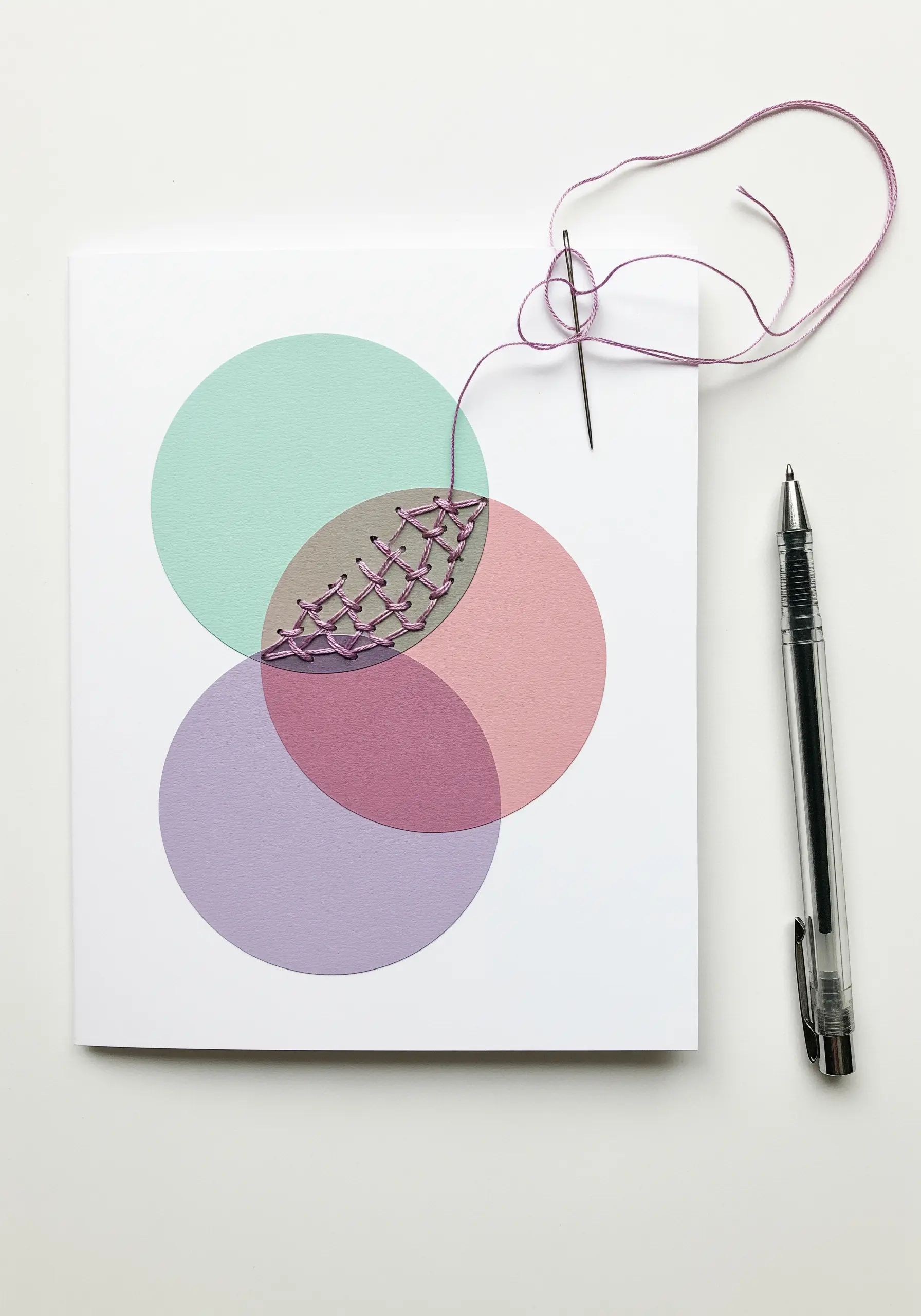 Three overlapping paper circles with the central intersecting area filled with purple embroidery.