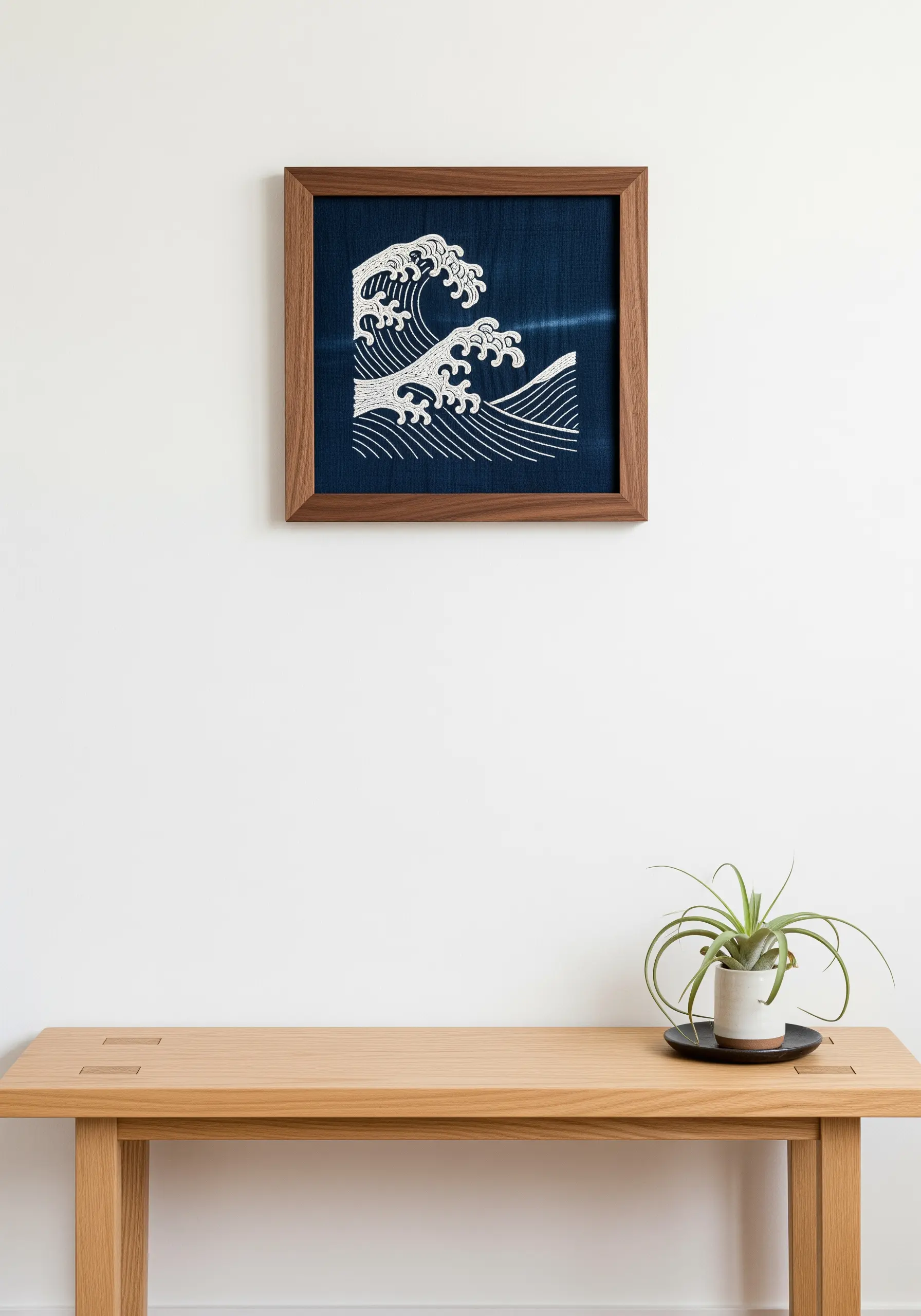 Japanese-style wave embroidery in white thread on dark indigo fabric, framed.