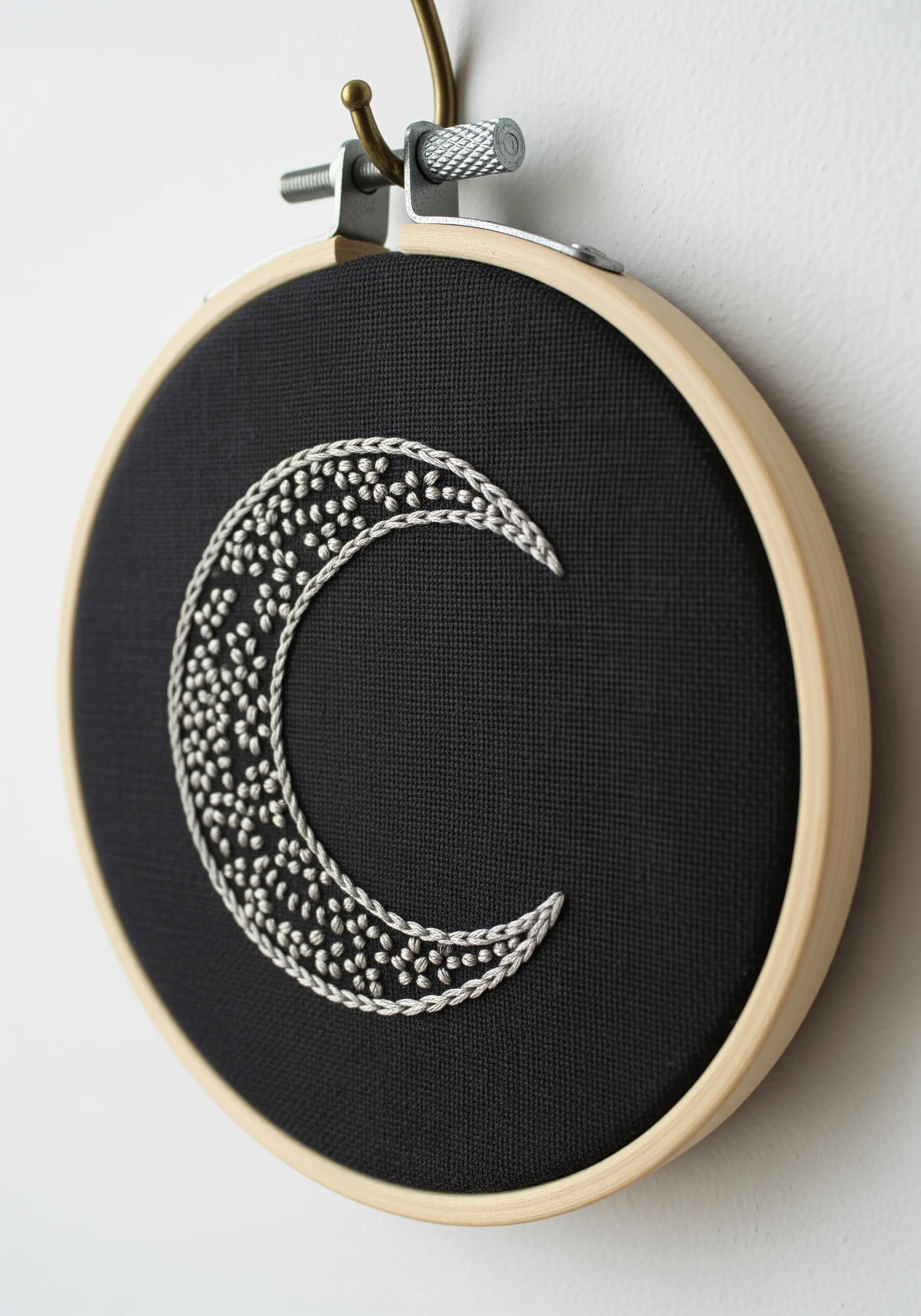 Crescent moon on black fabric, outlined in chain stitch and filled with French knots.