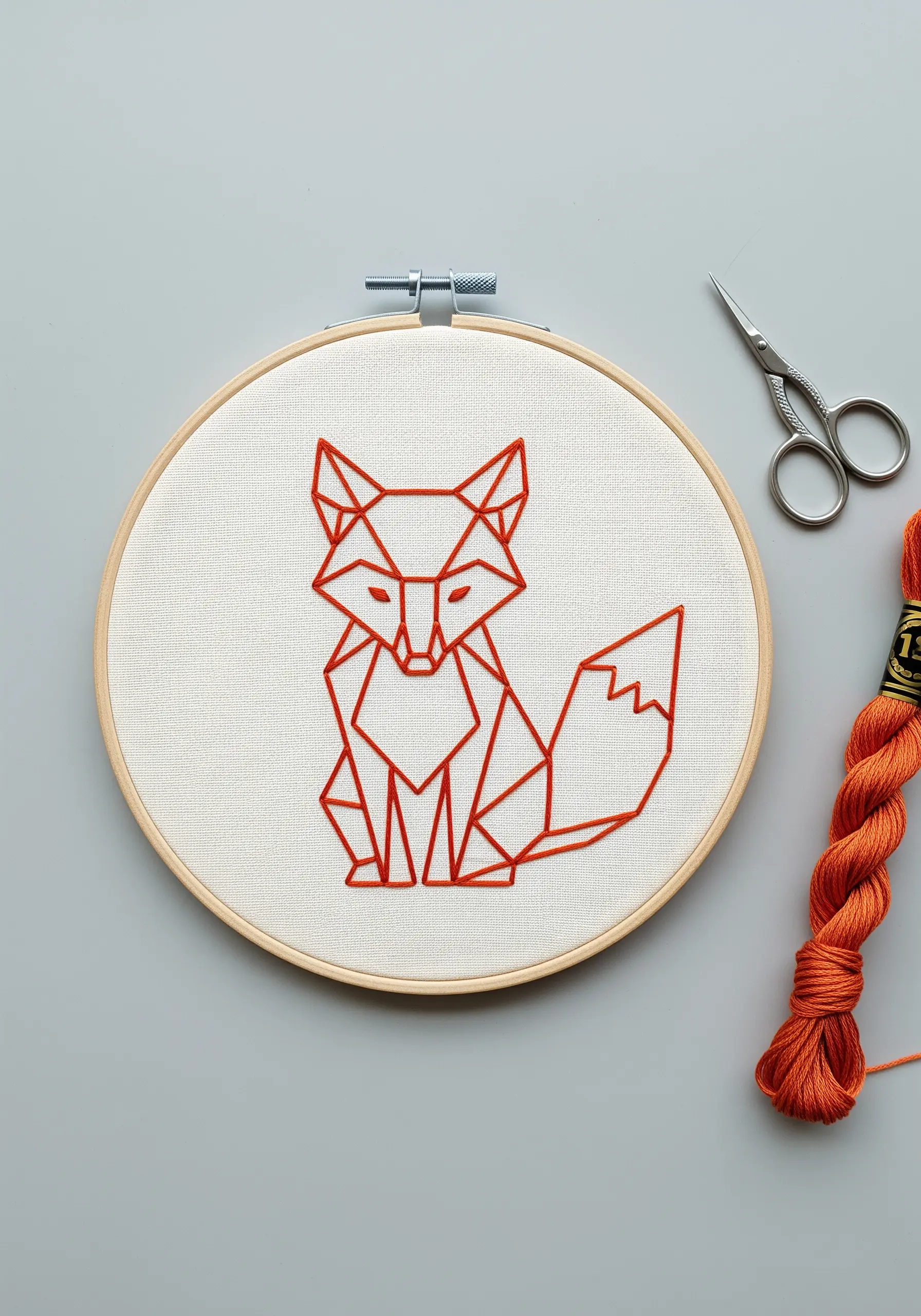 A geometric fox outlined in bright orange backstitch on a plain white fabric background.