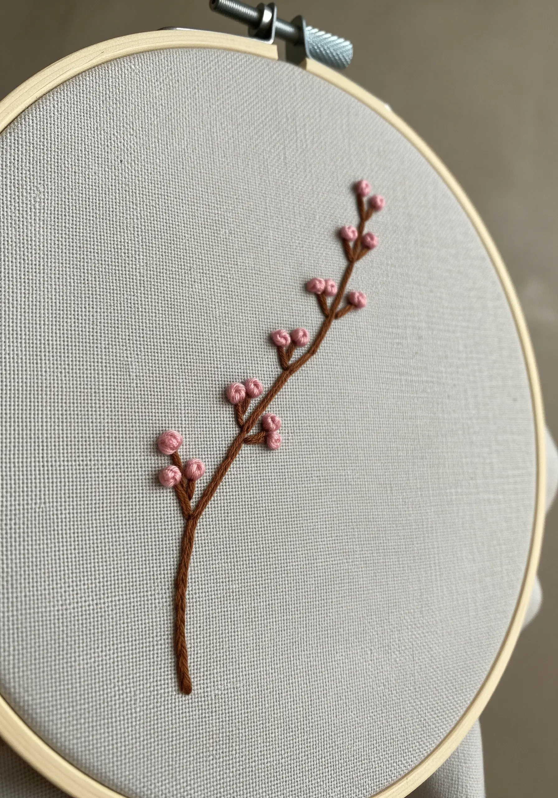 Embroidered cherry blossom branch with brown stem stitch and pink French knots.