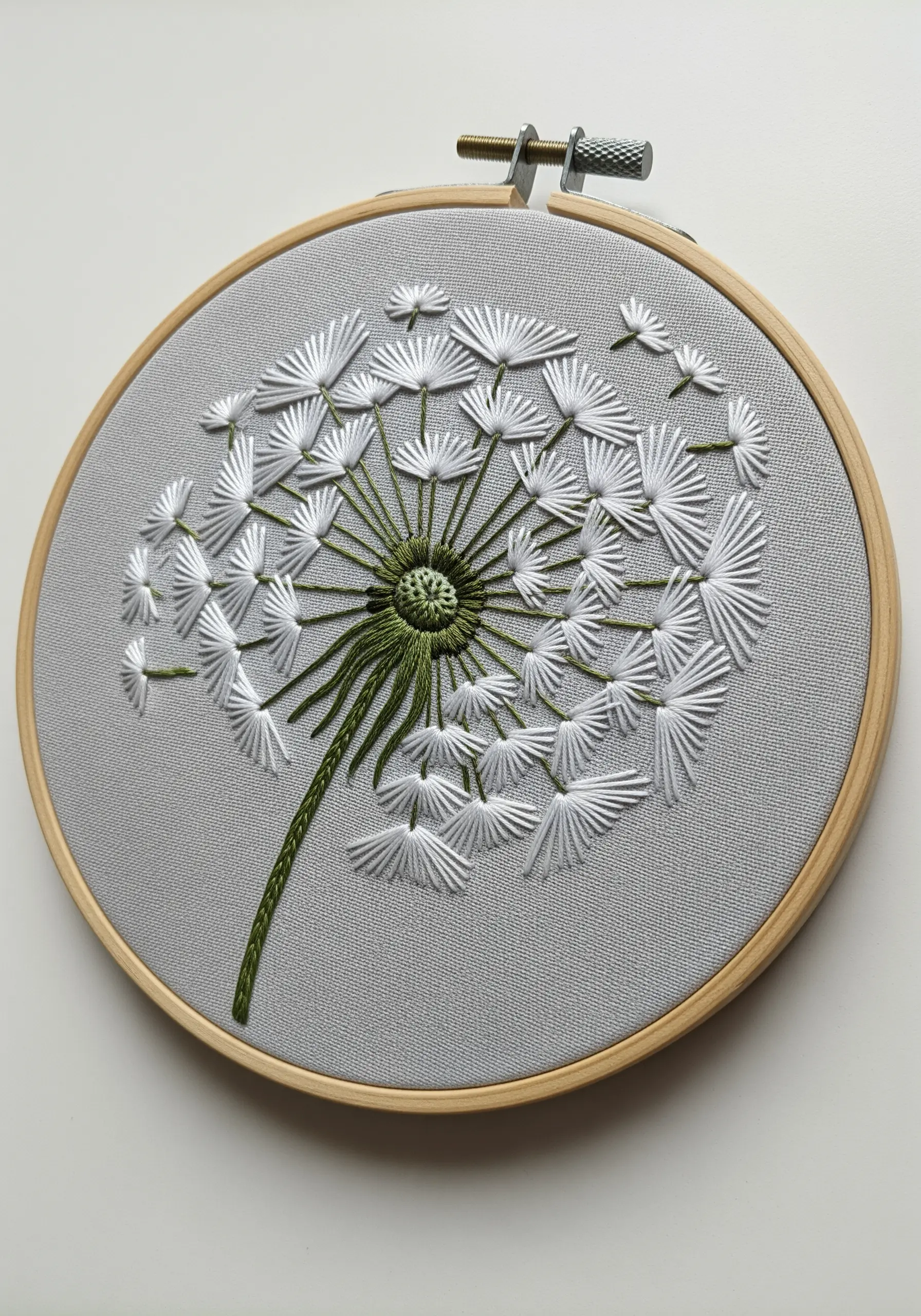 Detailed dandelion puff embroidery with white fly stitches and straight stitches.