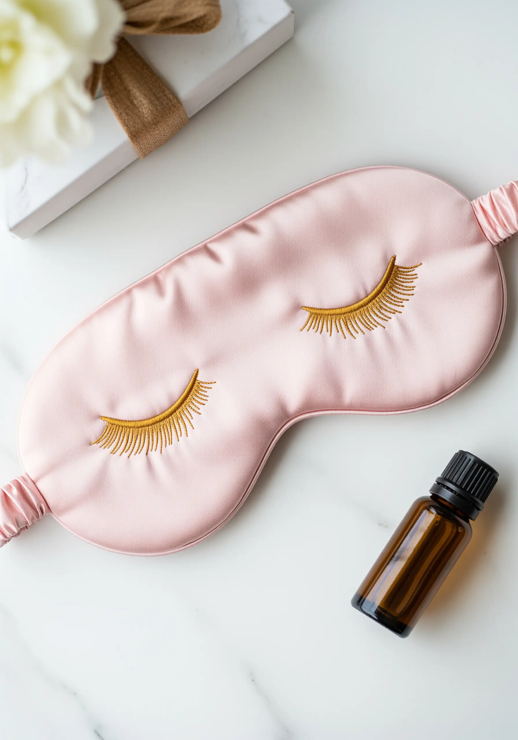 Gold thread embroidered eyelashes on a pink silk sleep mask