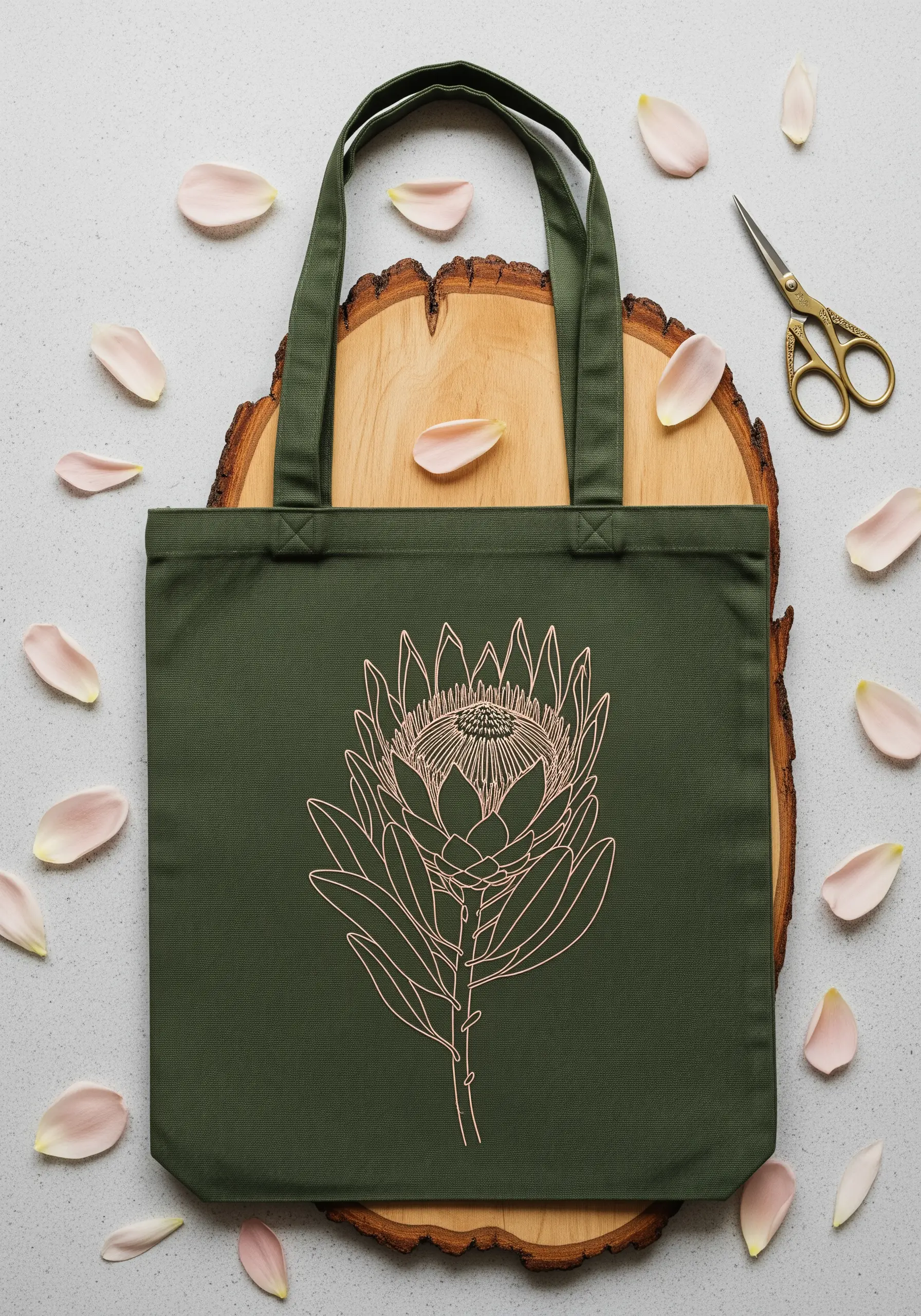 A line art protea flower embroidered in blush pink on an olive green tote.