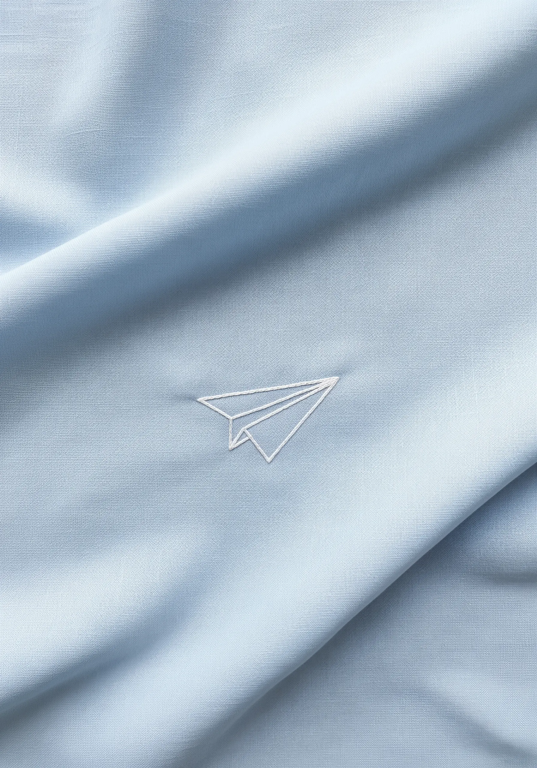 Minimalist white line art embroidery of a paper plane on a light blue scarf.