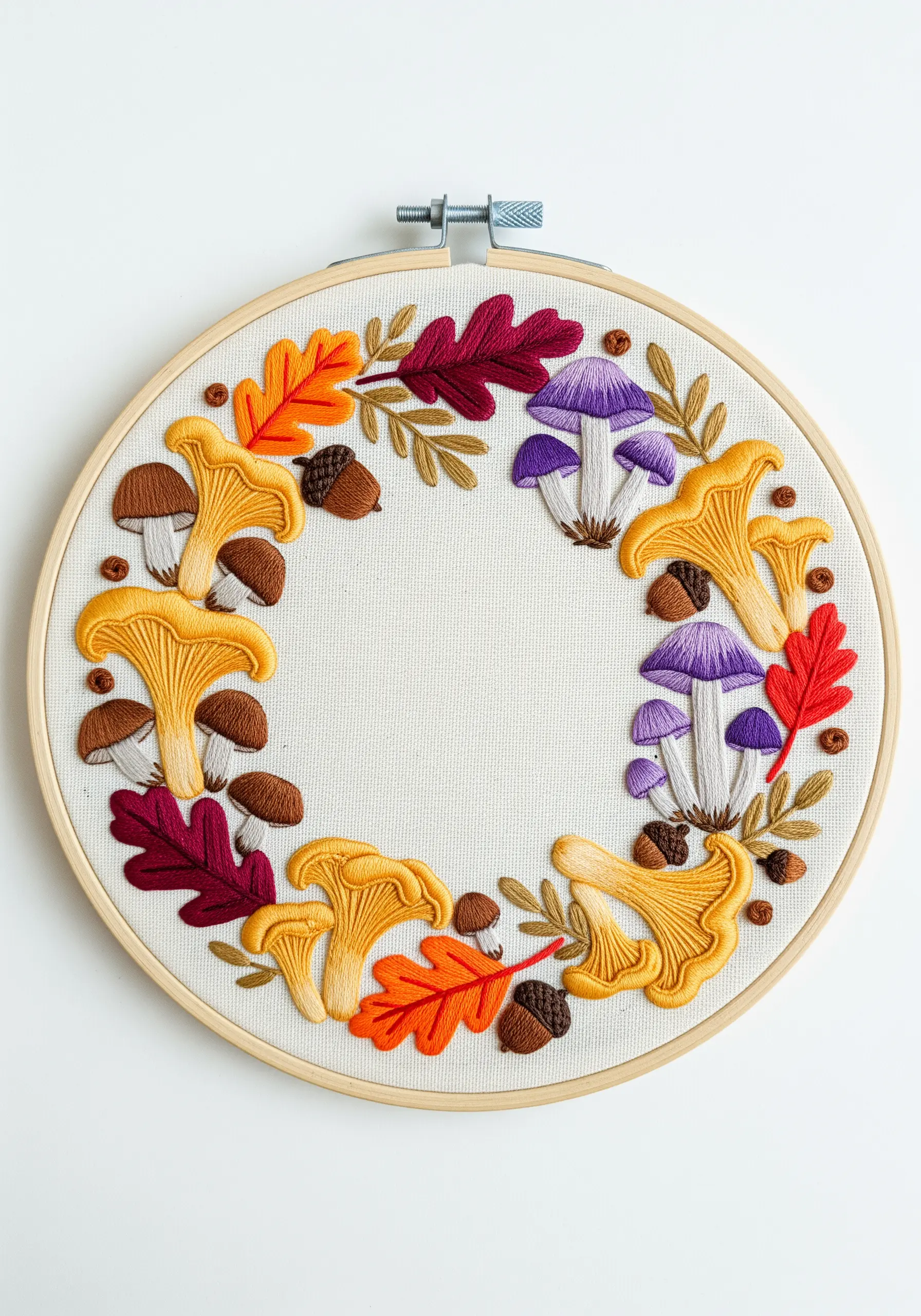 An embroidered wreath of autumn leaves, acorns, and various mushrooms on off-white fabric.