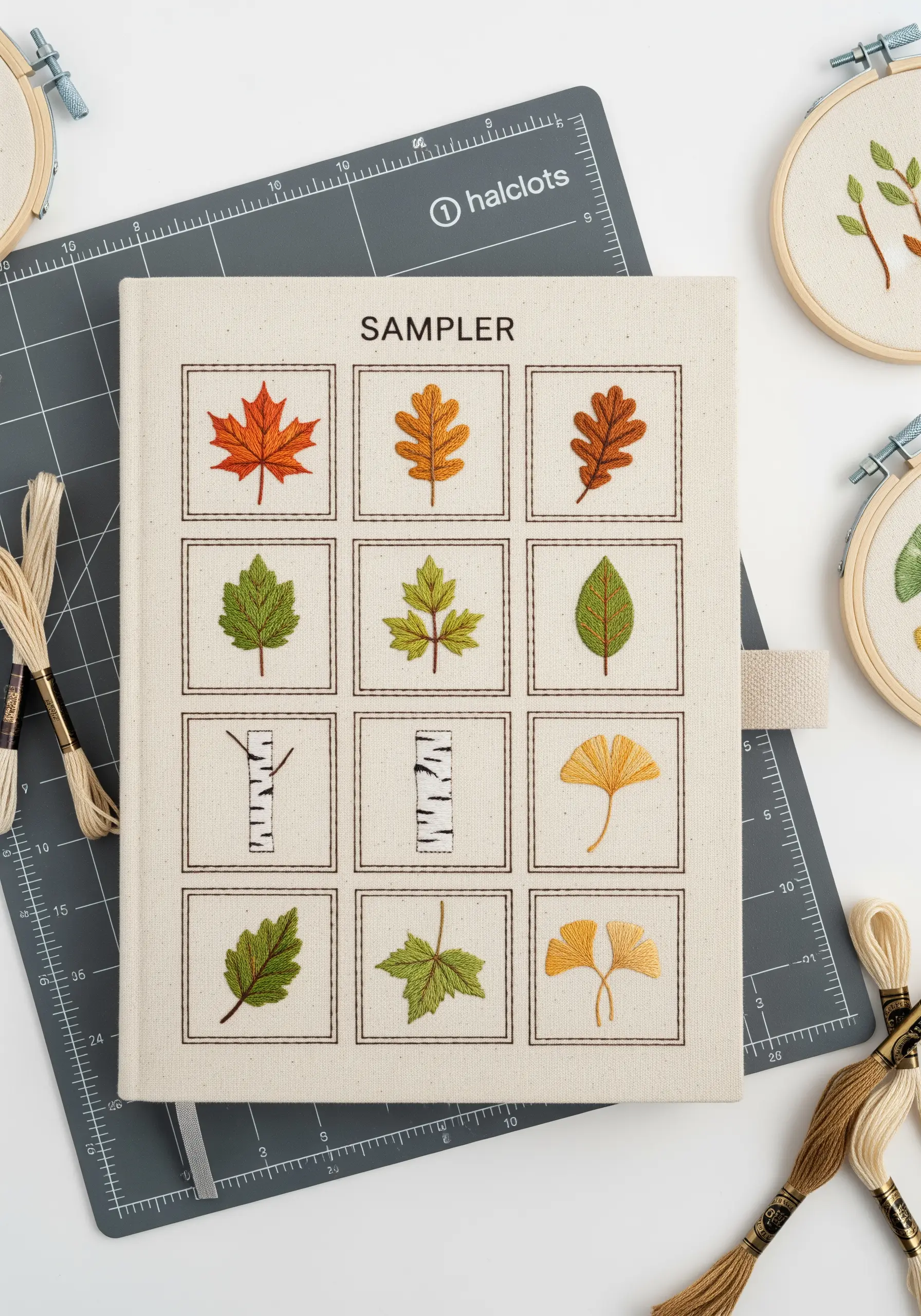 A sampler of nine different embroidered leaf types arranged in a grid on a journal.