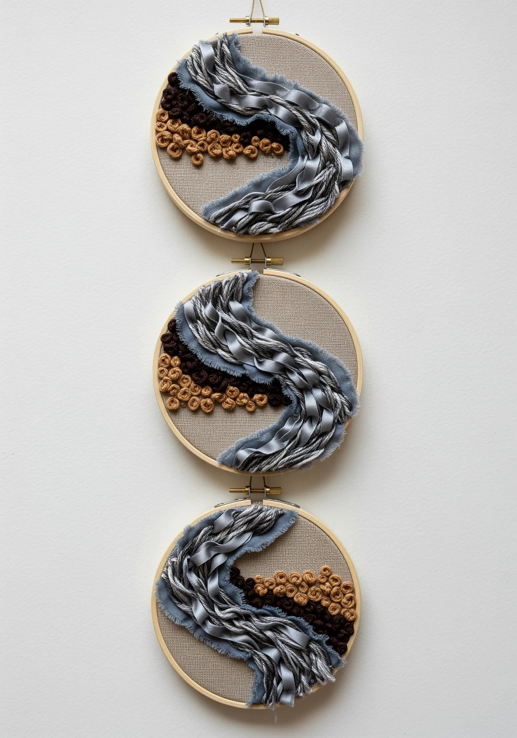 A triptych of three embroidery hoops showing a continuous design of gray ribbon and brown knots.