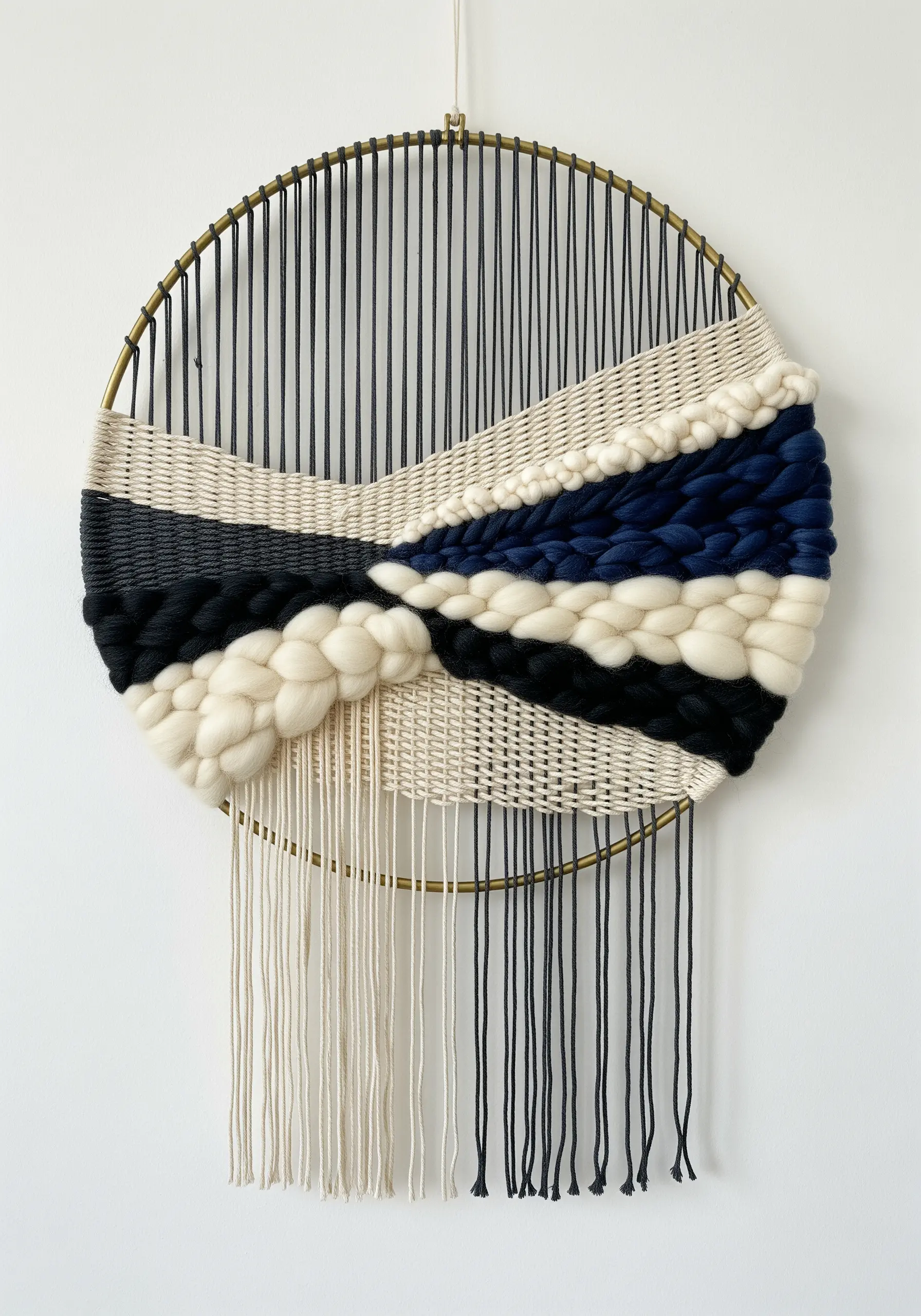 Circular weaving on a metal hoop with navy, black, and cream wool roving.