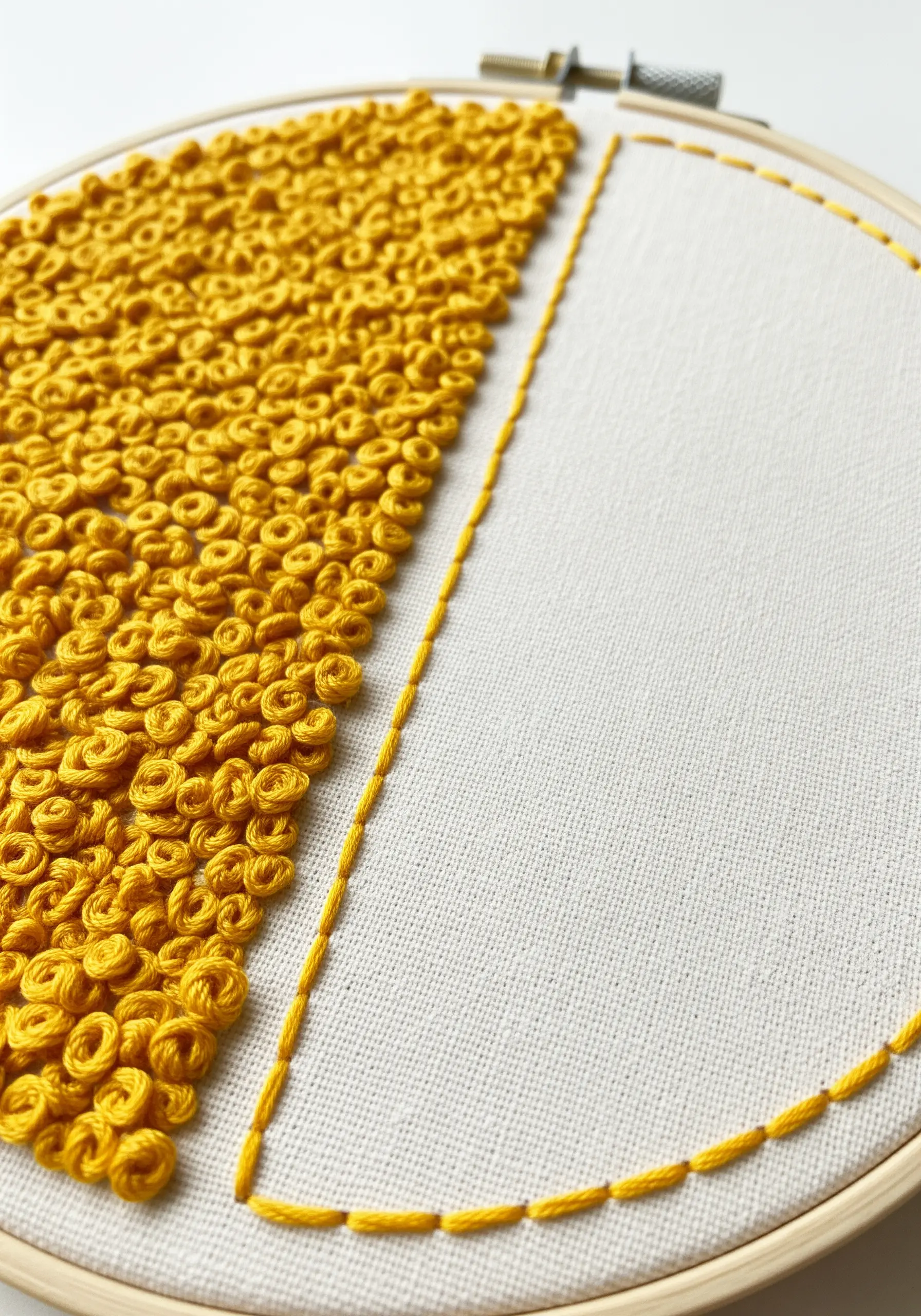 A hoop split in half: one side filled with yellow French knots, the other outlined.