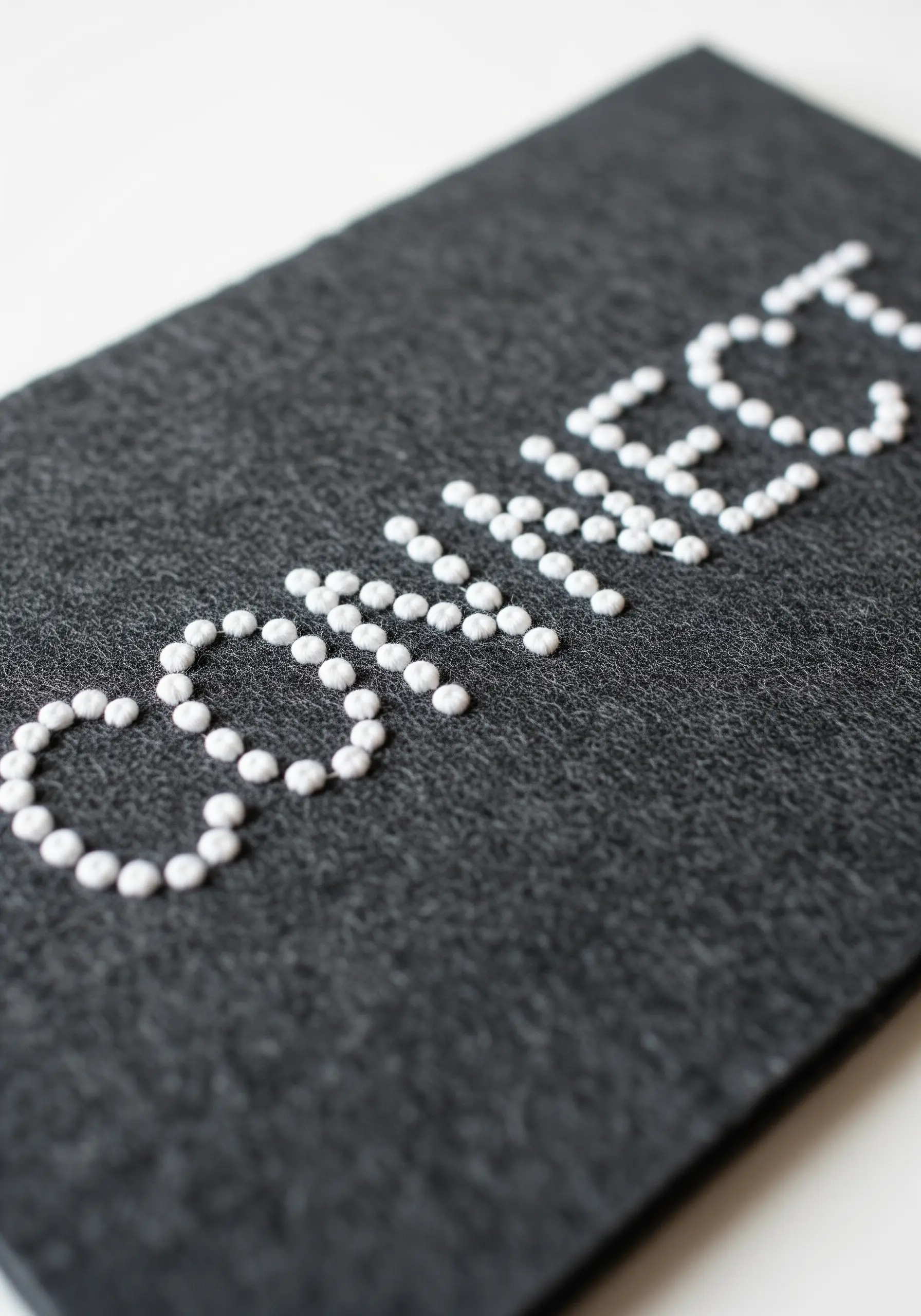 The word connect spelled out in white French knots or beads on dark gray felt.