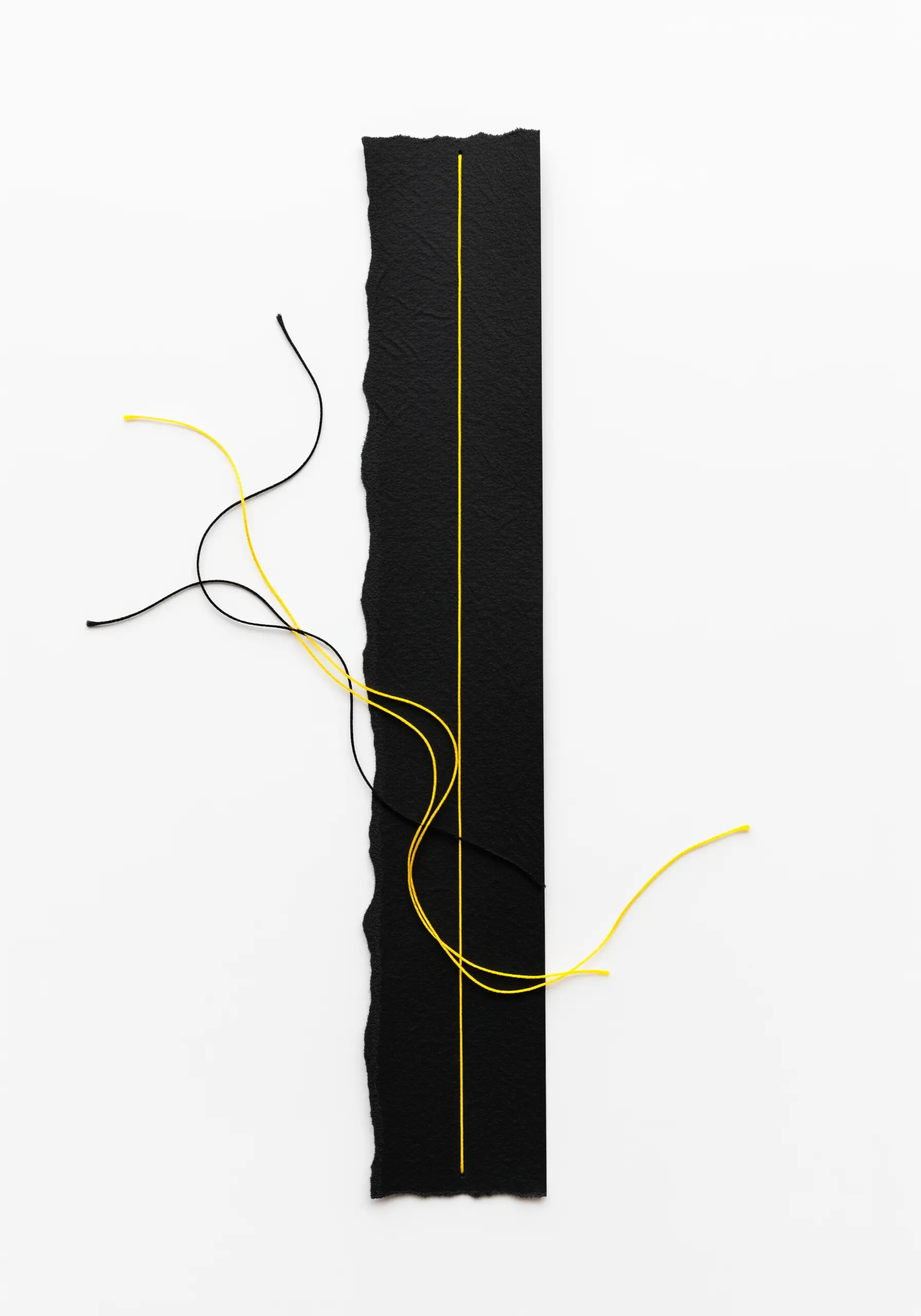 Minimalist art with a straight yellow stitched line on black paper, contrasted by loose threads.