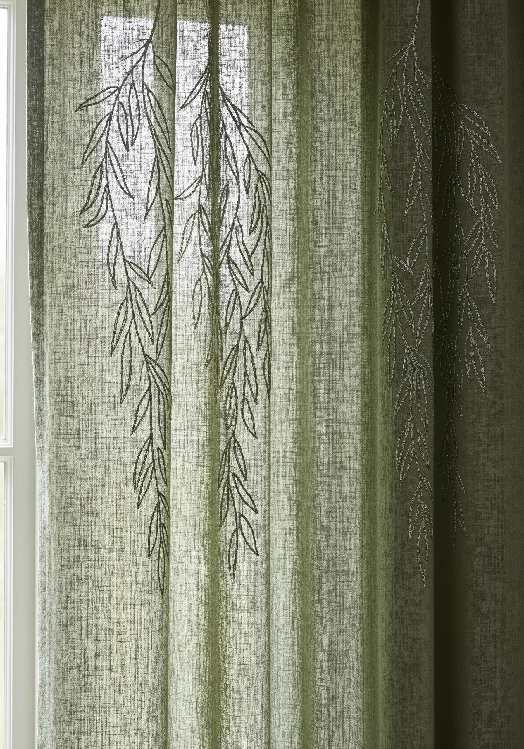 Sheer green curtain with embroidered outlines of weeping willow branches.