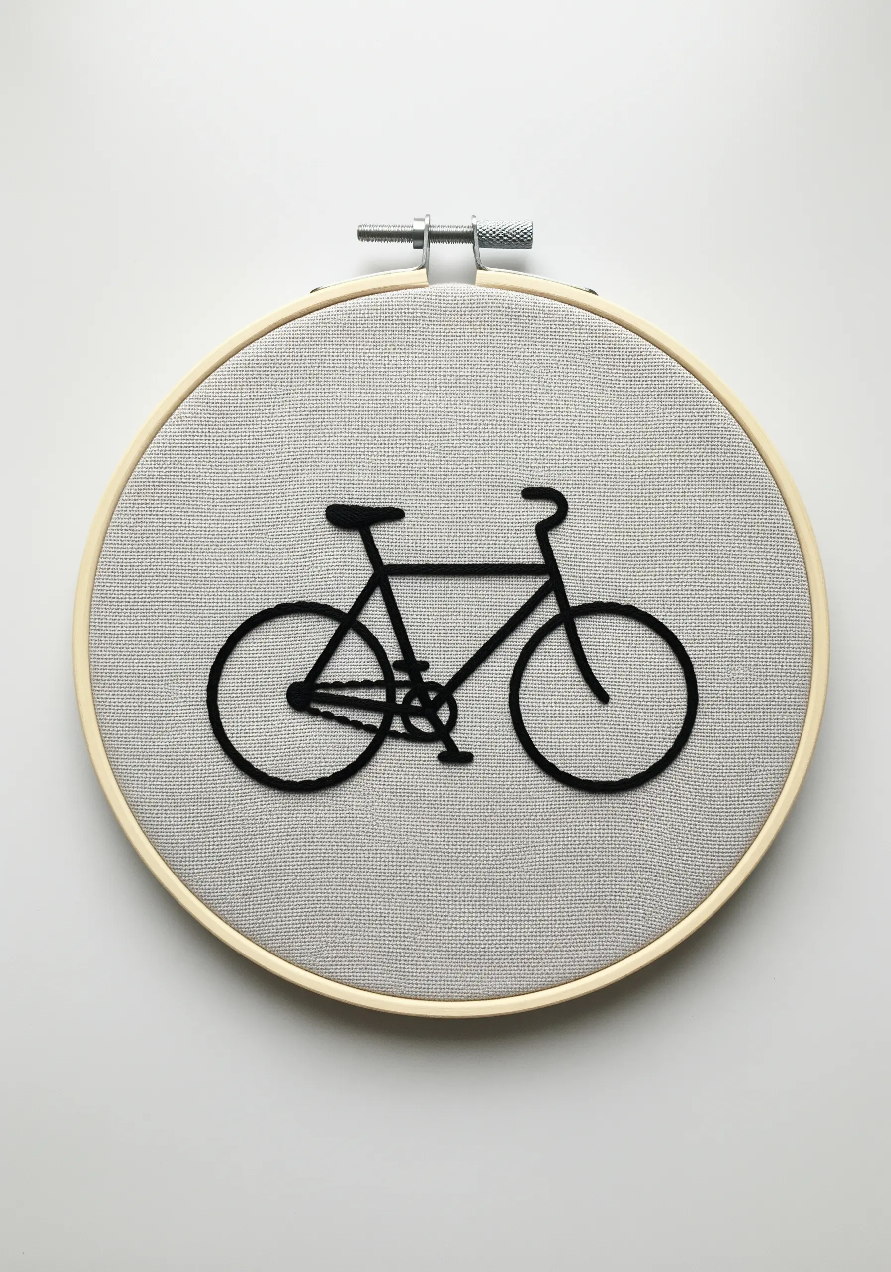A bold black bicycle silhouette created with a raised, padded satin stitch on gray fabric.