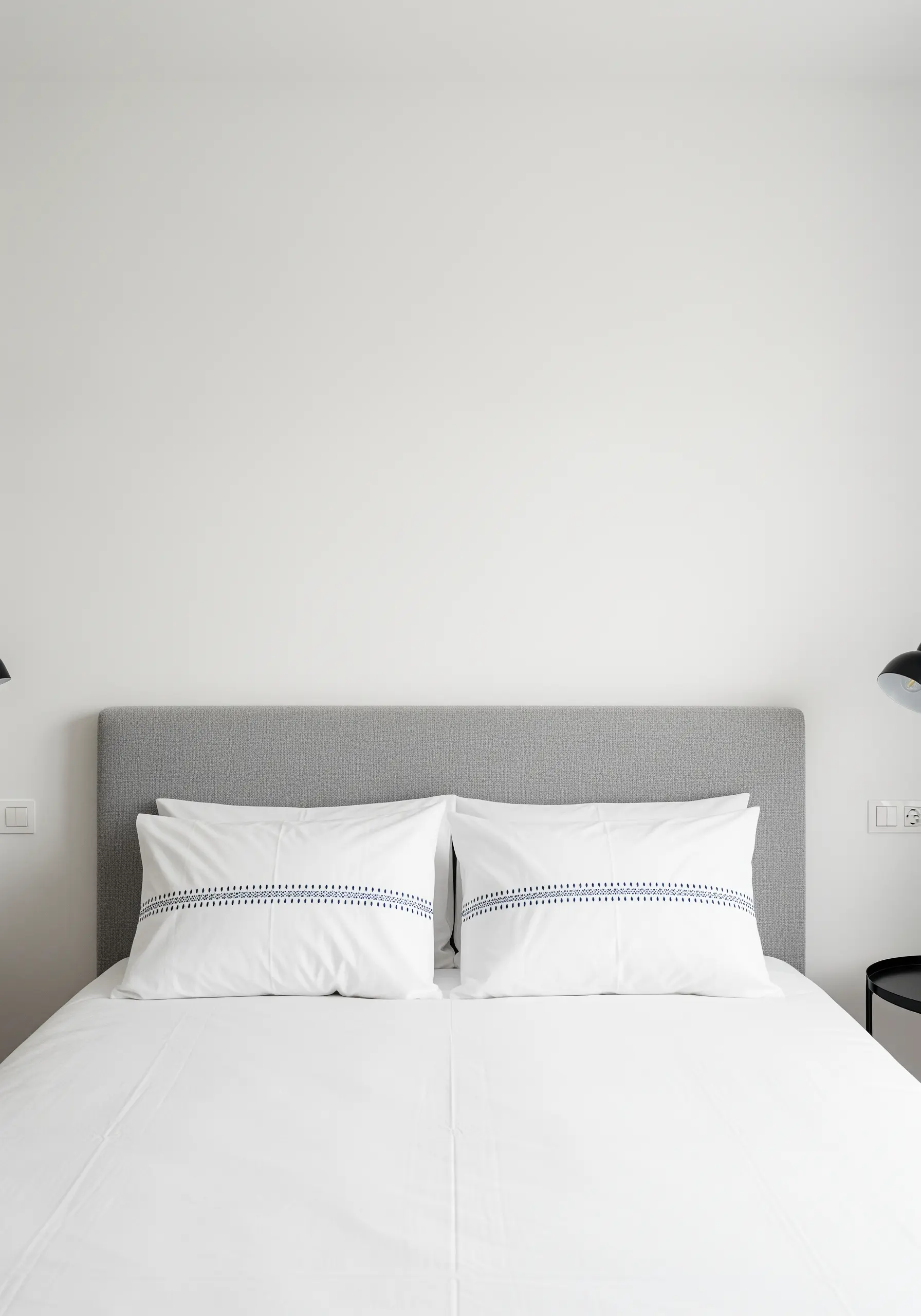 White pillows on a bed with a simple, horizontal band of decorative black stitching