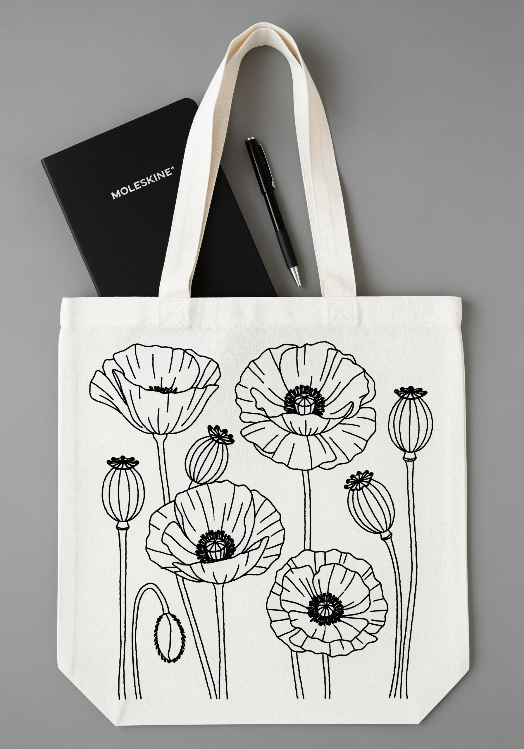 Black line-art embroidery of poppy flowers and seed pods on a white tote bag